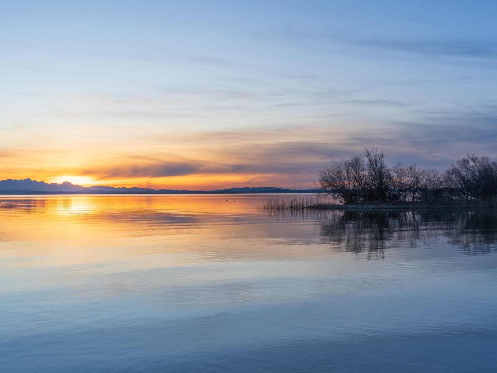 Рассвет над тихой гладью озера летом