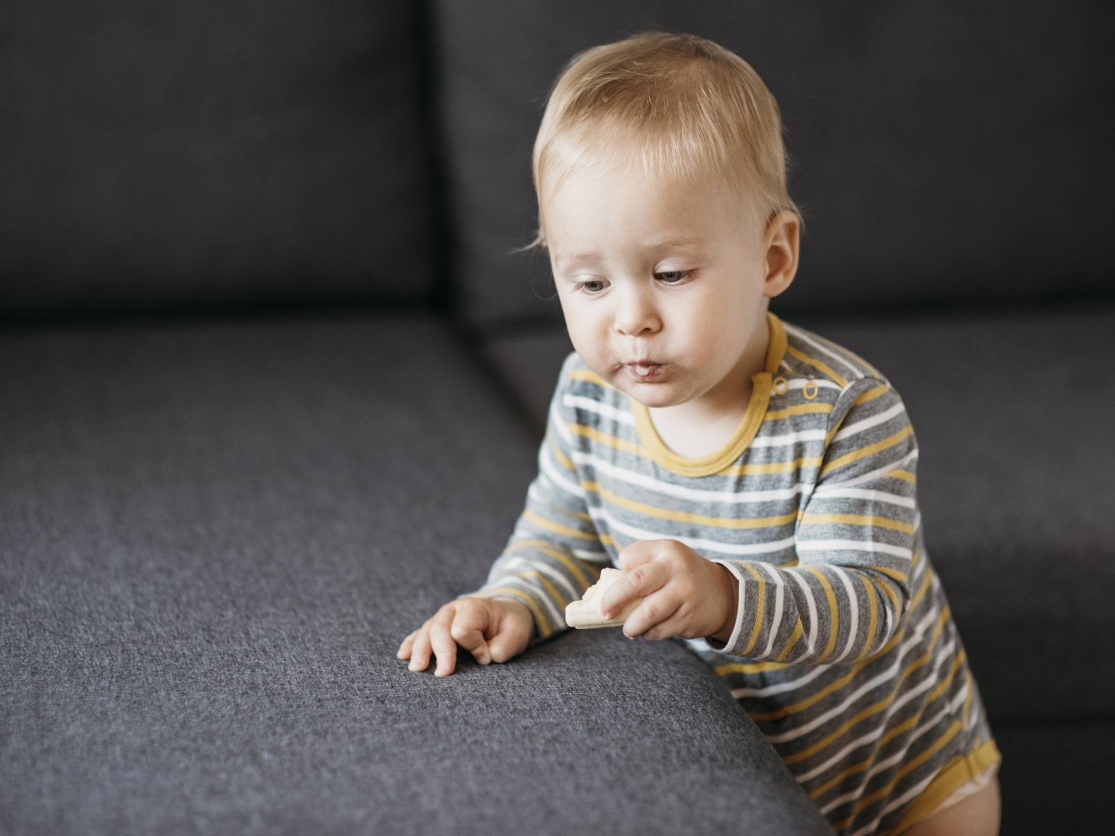 Любопытный маленький ребенок у дивана