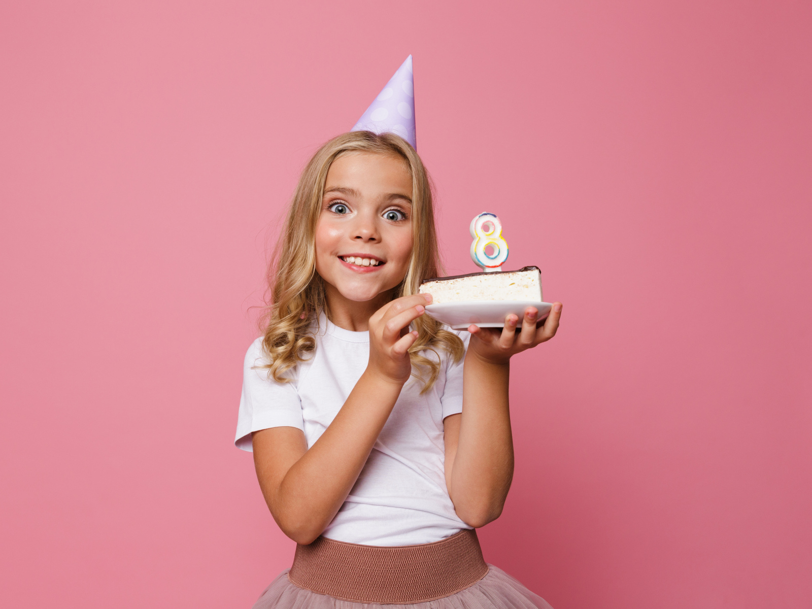 Милая девочка отмечает день рождения на розовом фоне