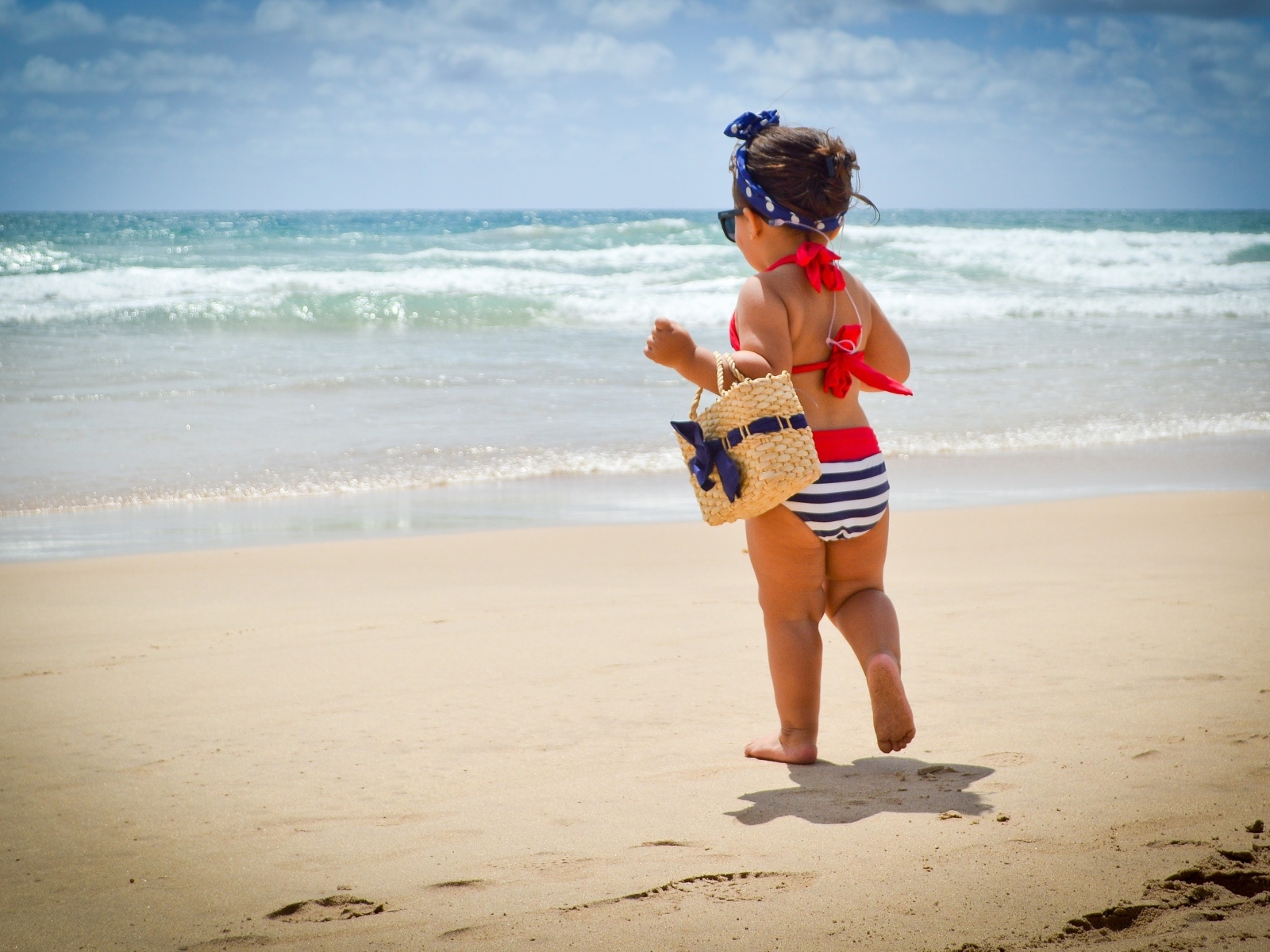 Модная маленькая девочка с сумочкой на берегу моря