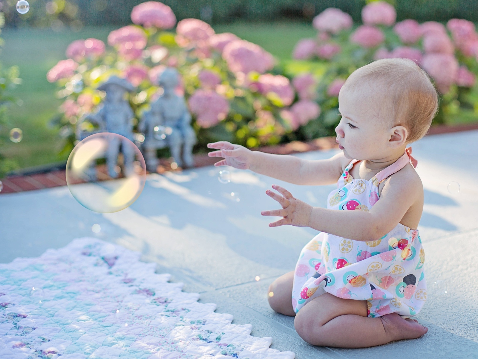 Маленькая девочка ловит мыльный пузырь