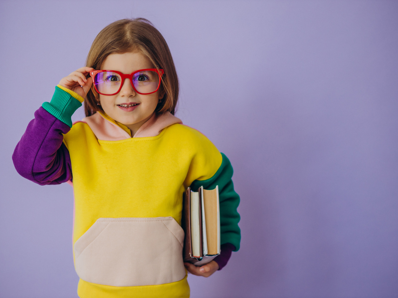 Маленькая девочка в очках с книгами в руке