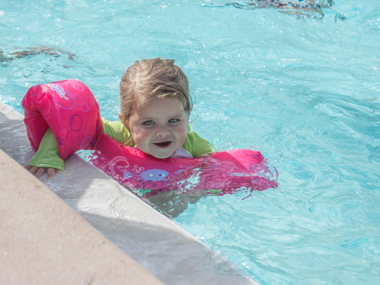 Маленькая девочка со спасательным кругом в бассейне