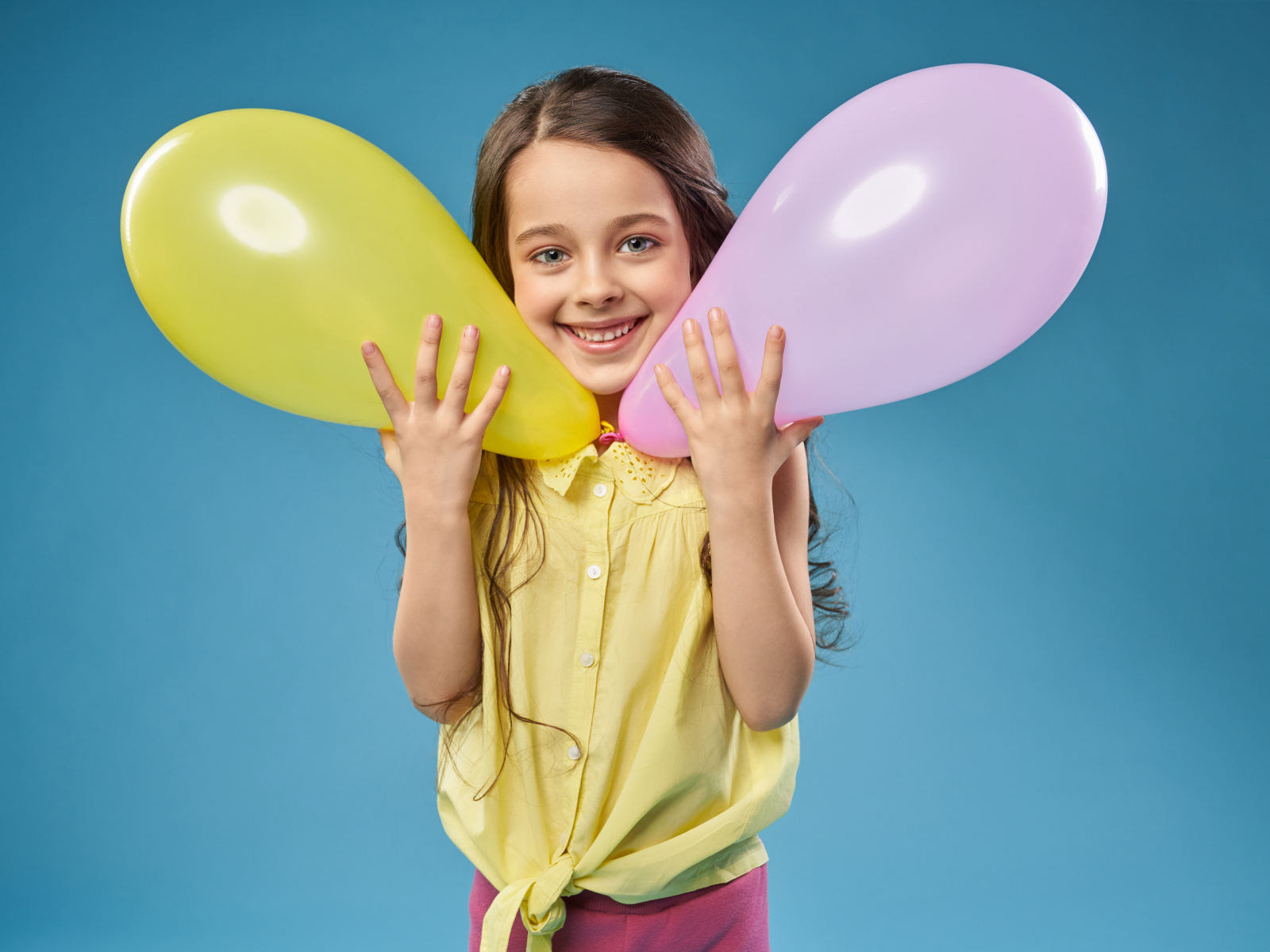 Маленькая девочка с воздушными шариками на голубом фоне