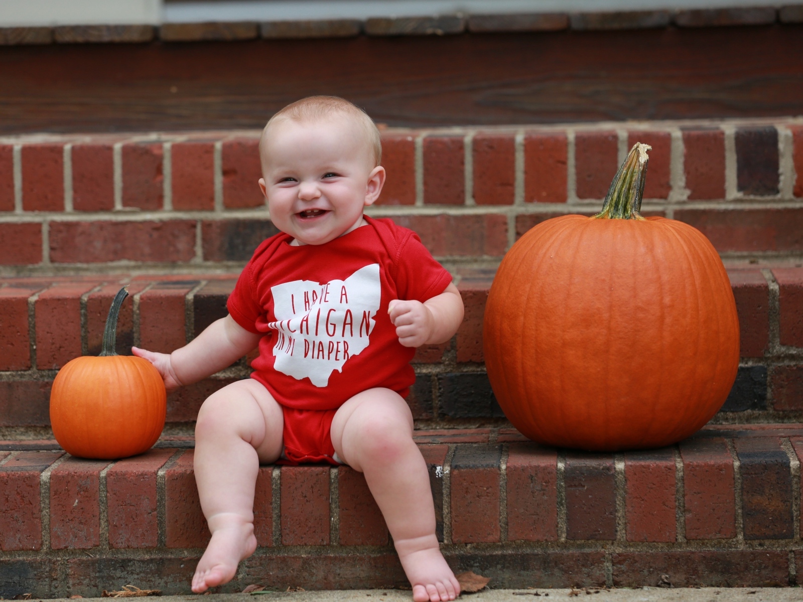 Маленький улыбающийся ребенок с тыквами на ступенях