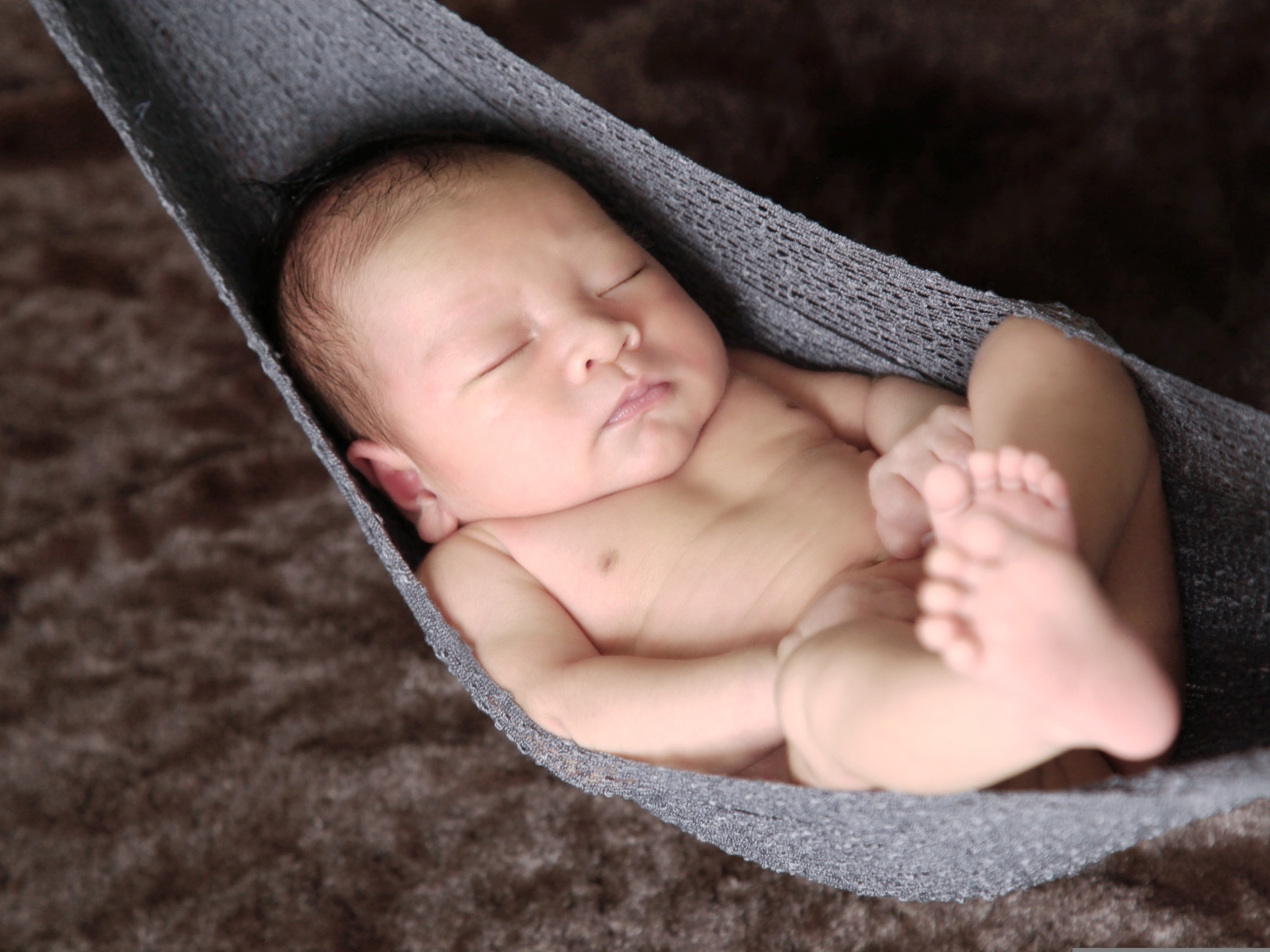 Новорожденный спящий малыш в вязаном гамаке