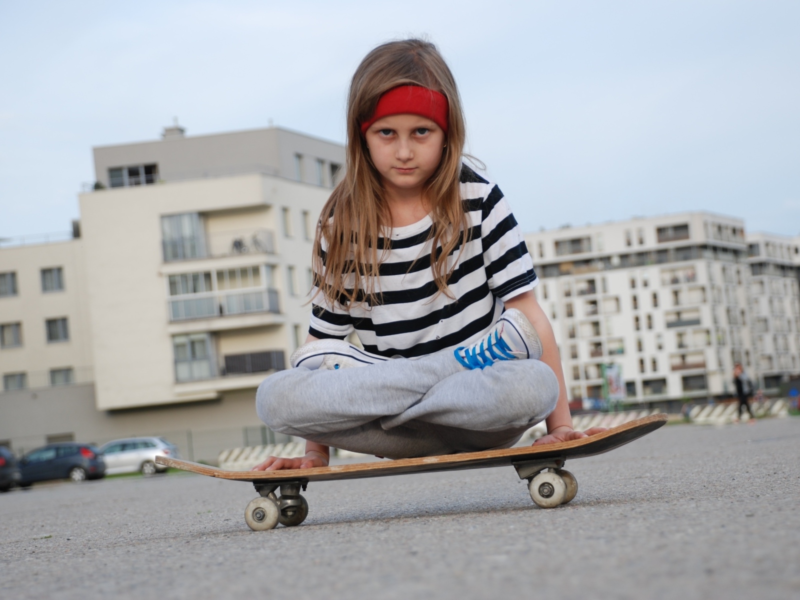 Серьезная девочка сидит на  скейтборде