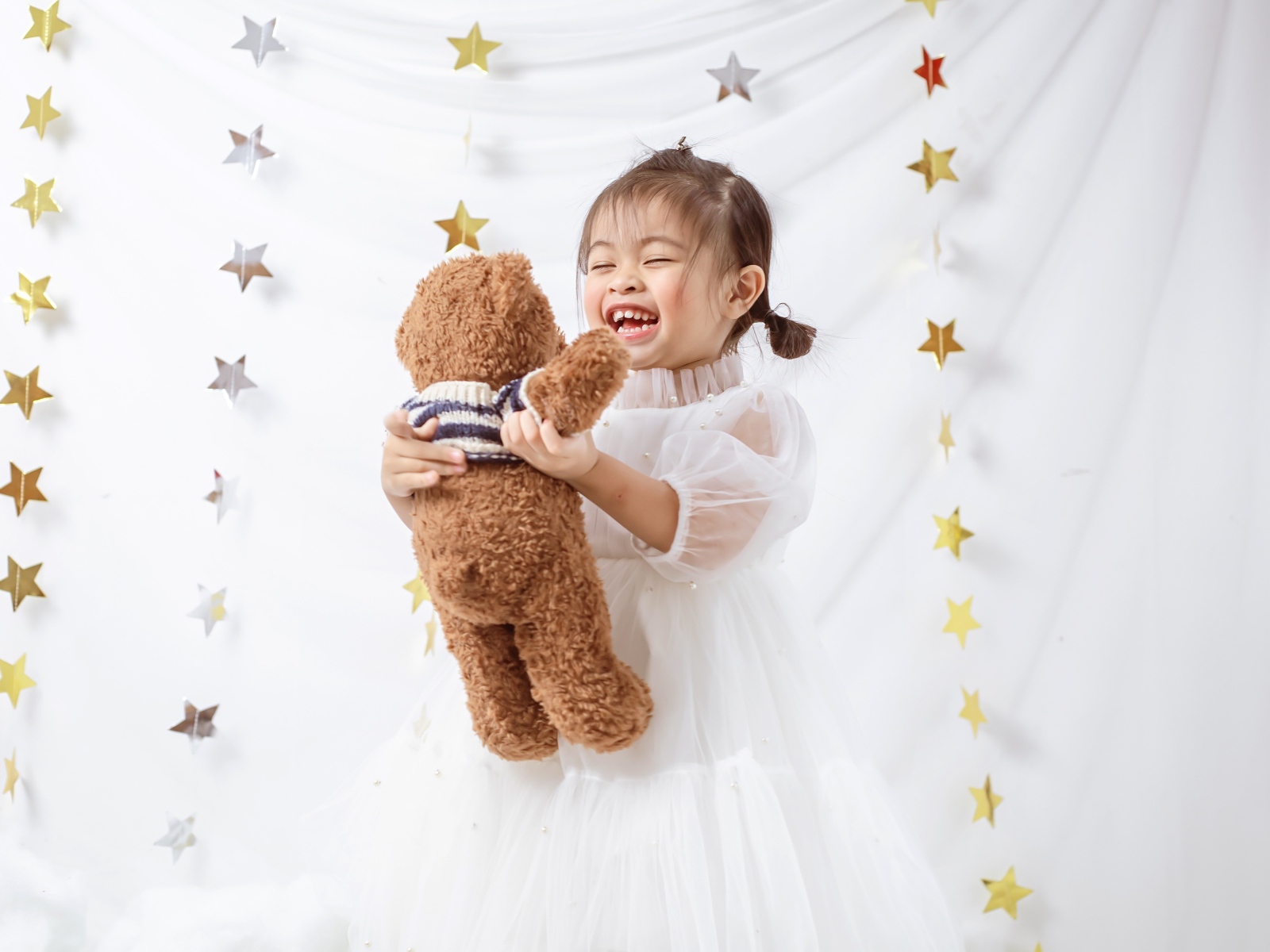 Улыбающаяся девочка азиатка с игрушечным медведем