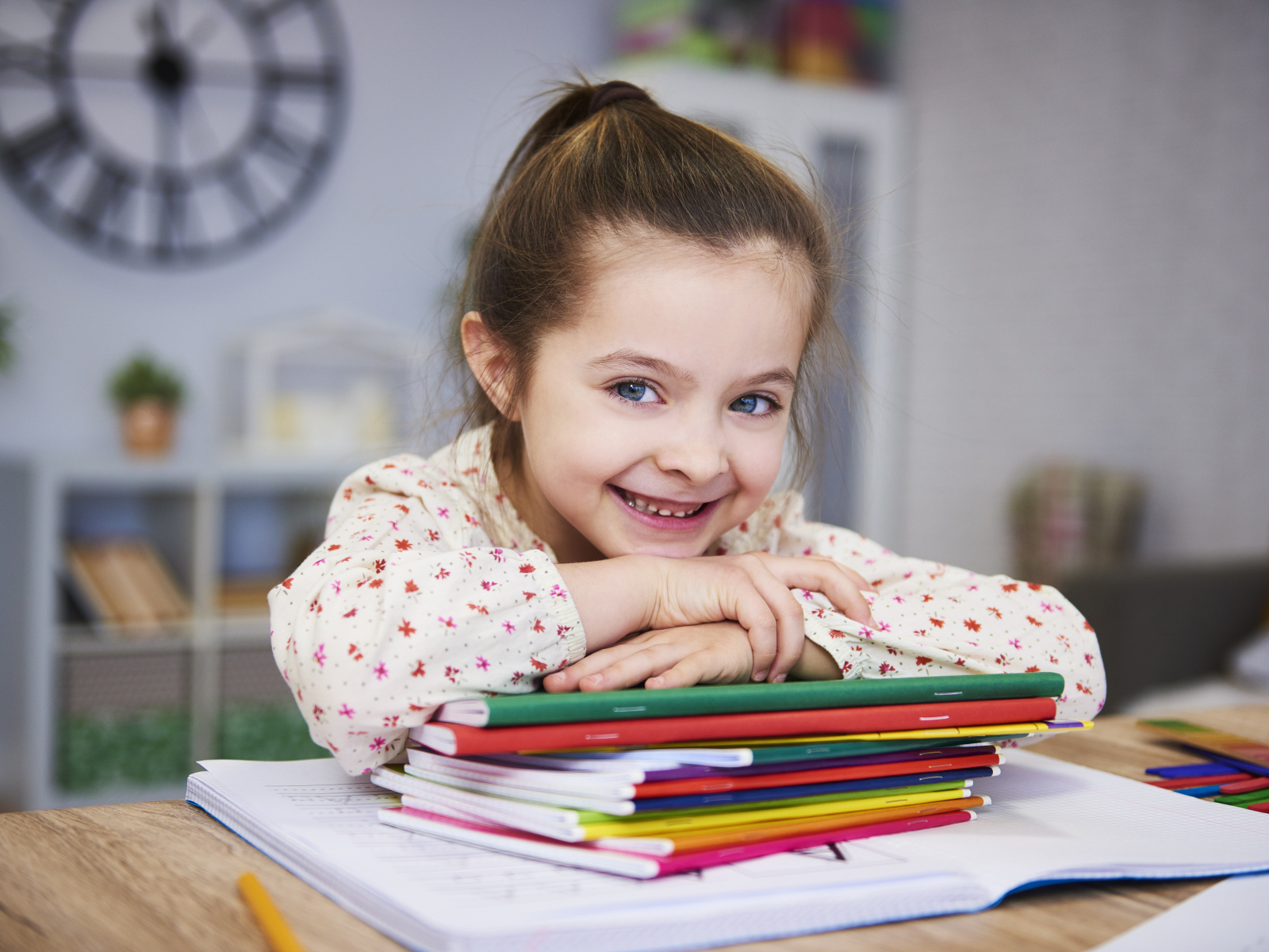 Улыбающаяся девочка ученица  с тетрадями за столом