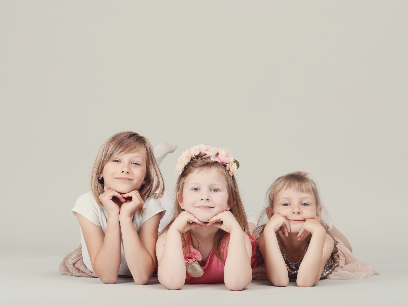 Три маленькие девочки лежат на сером фоне