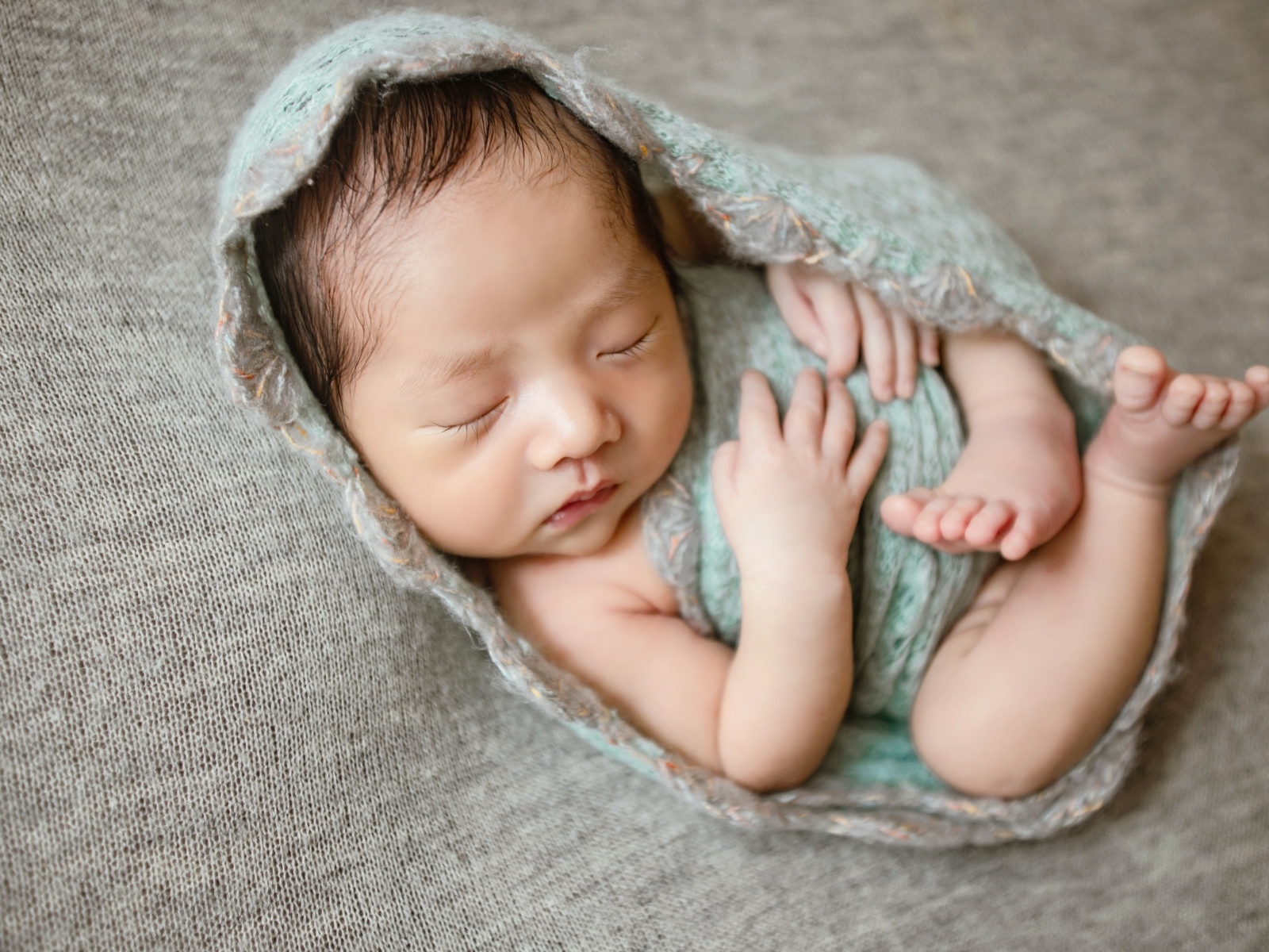 Крошечный новорожденный малыш на сером фоне