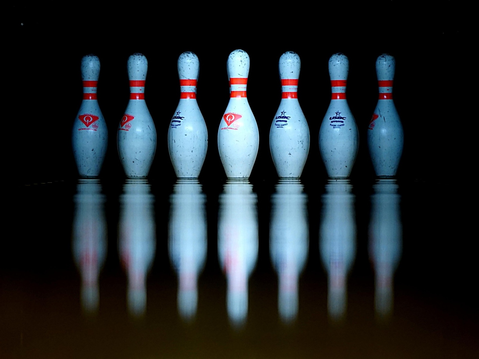 Кегли для боулинга отражаются в черной поверхности 