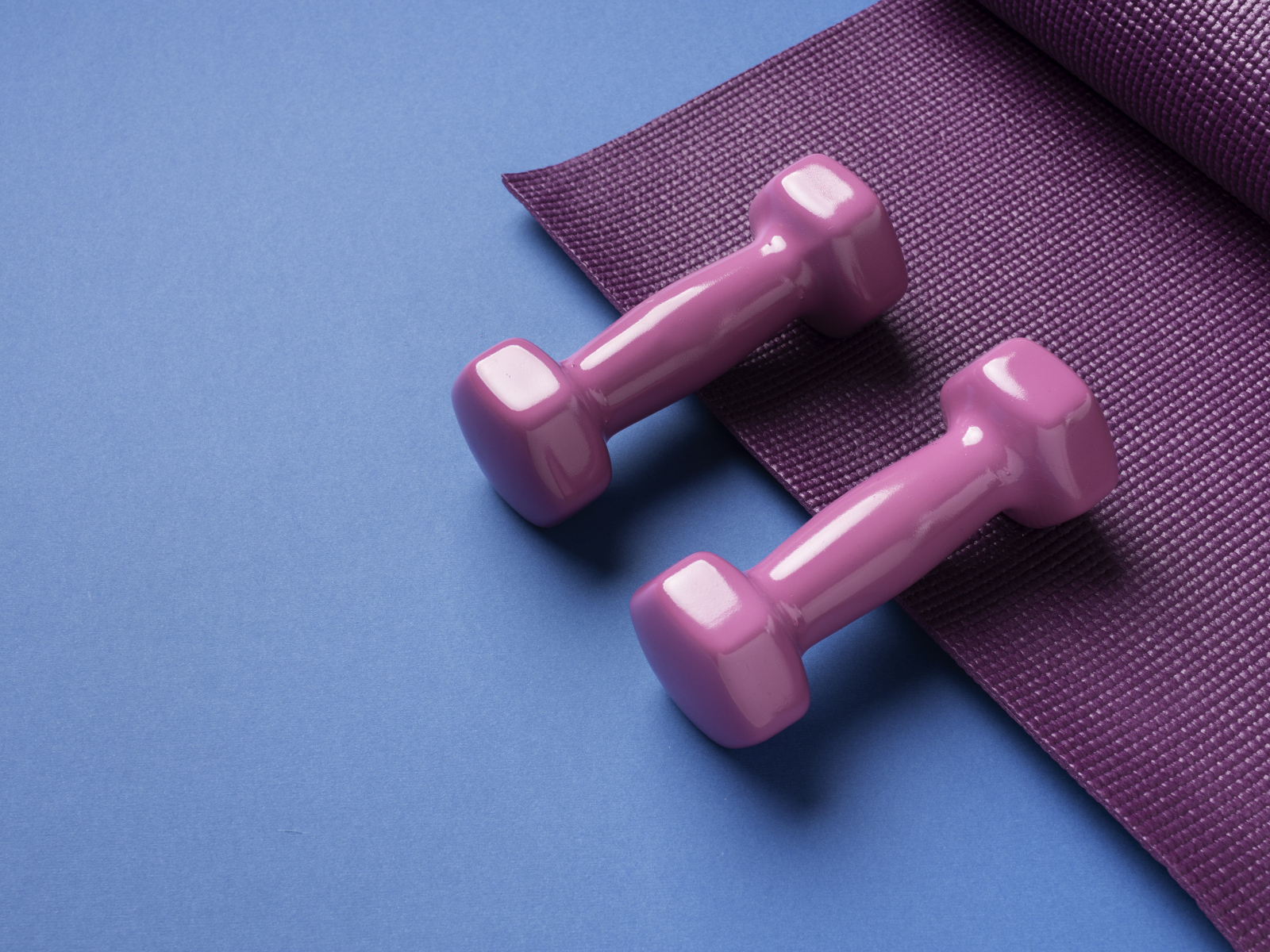 Розовые гантели и коврик на голубом фоне