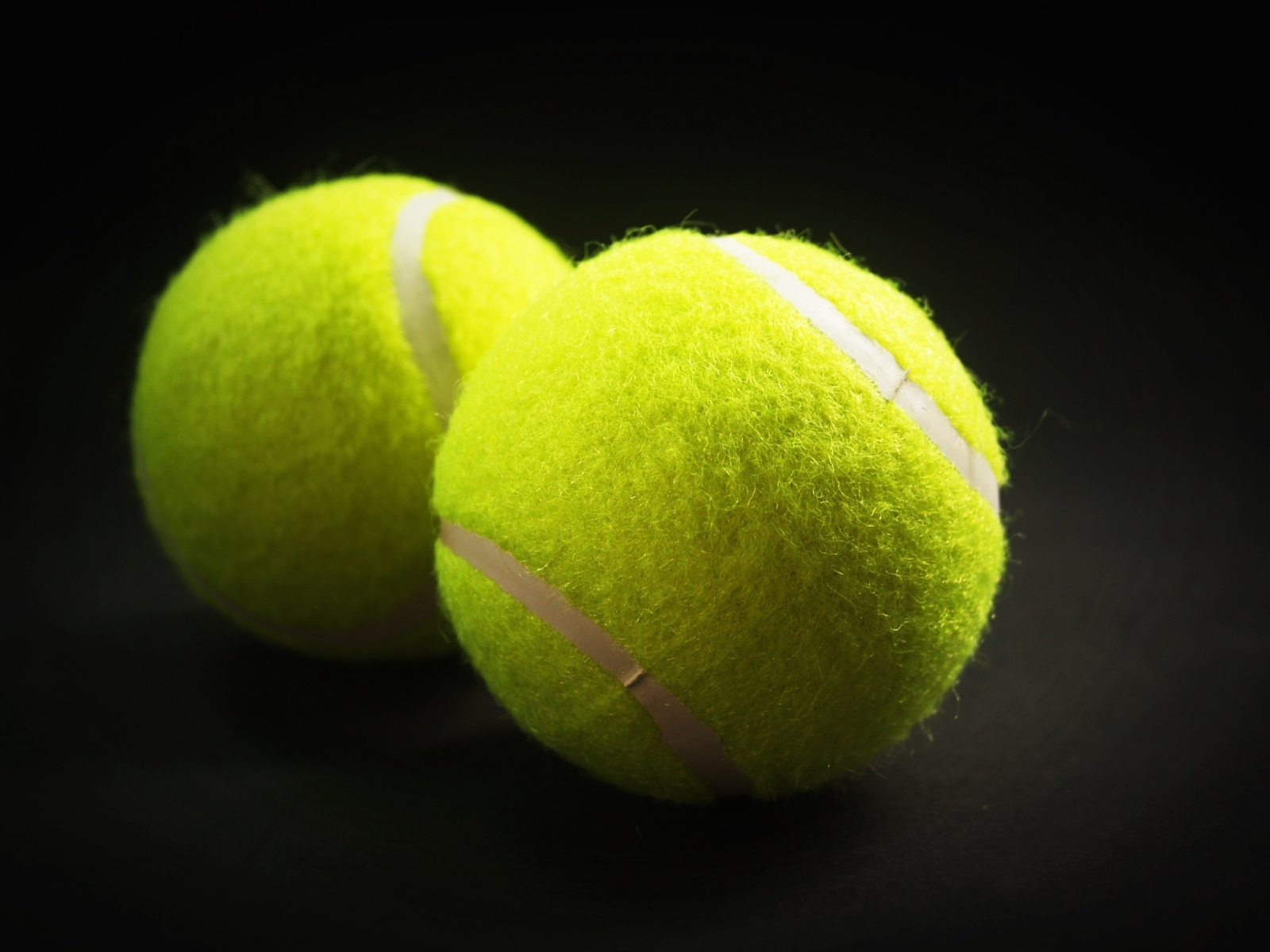 Два желтых теннисных мячика на сером фоне