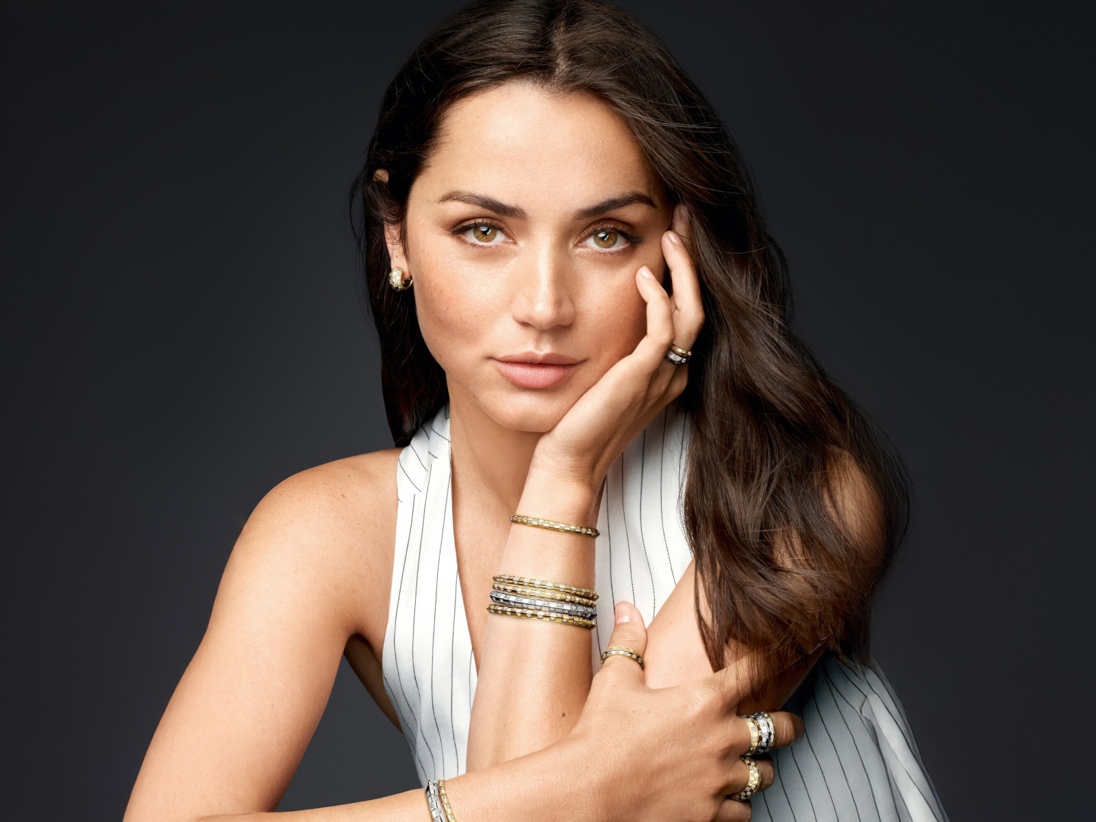 Актриса Ана де Армас с украшениями на руках на сером фоне