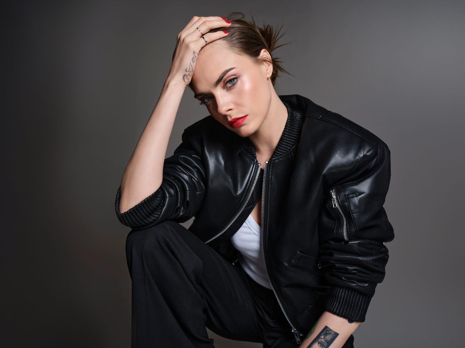 Актриса Кара Делевинь в черной кожаной куртке на сером фоне