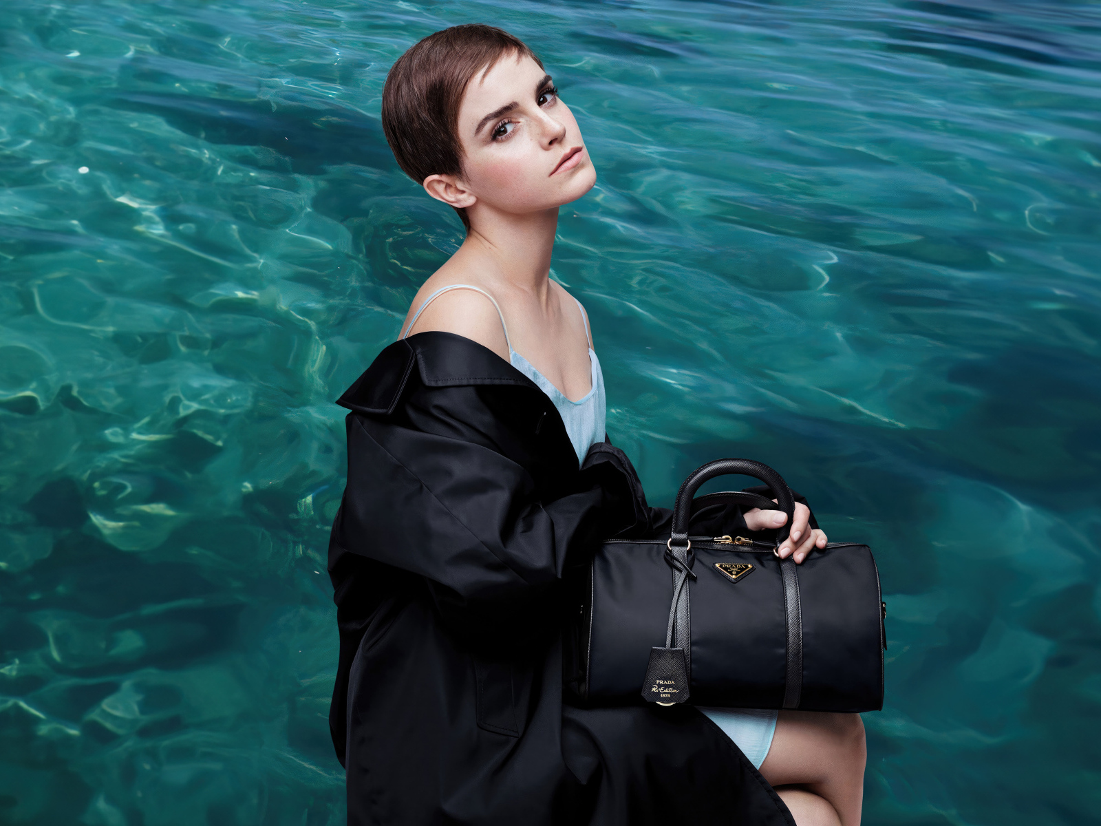 Актриса Эмма Уотсон с сумочкой сидит у воды