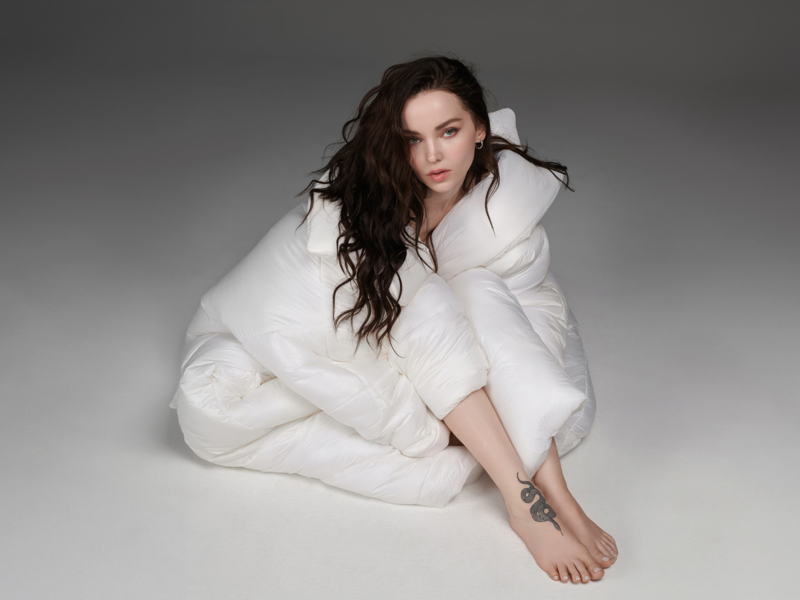 Красивая брюнетка Дав Кэмерон в белом костюме на сером фоне