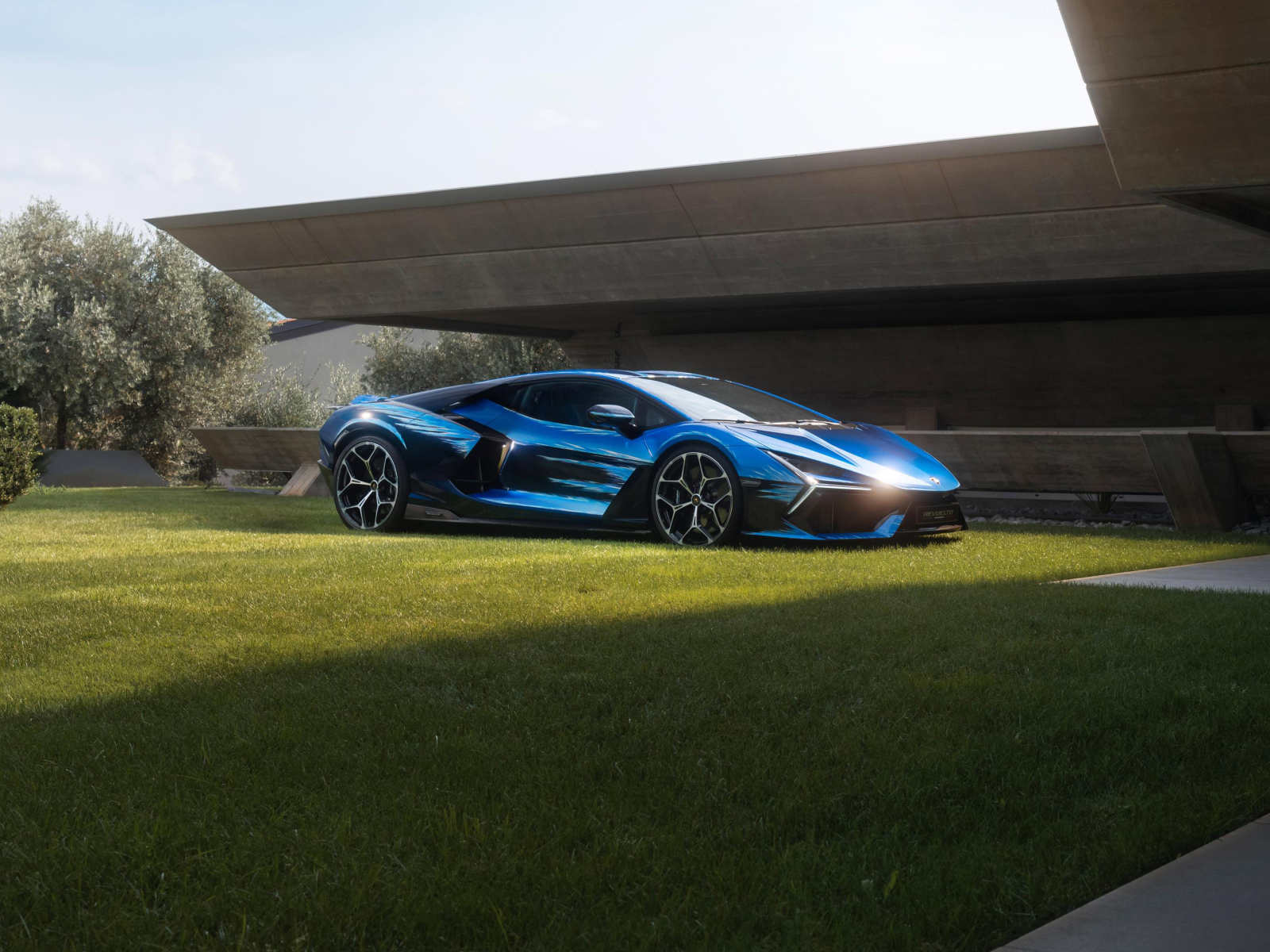 Синий Lamborghini Revuelto Opera Unica 2024 года на зеленой траве