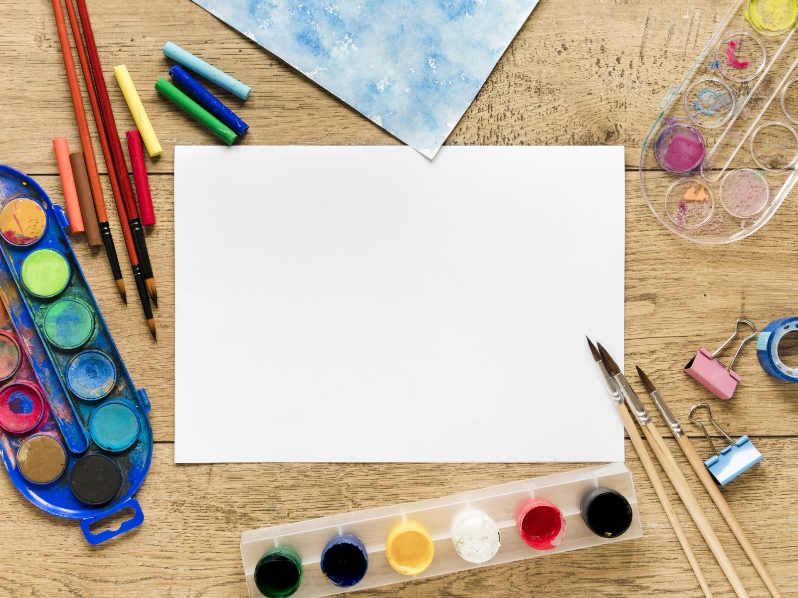 Предметы для рисования с листом бумаги на столе