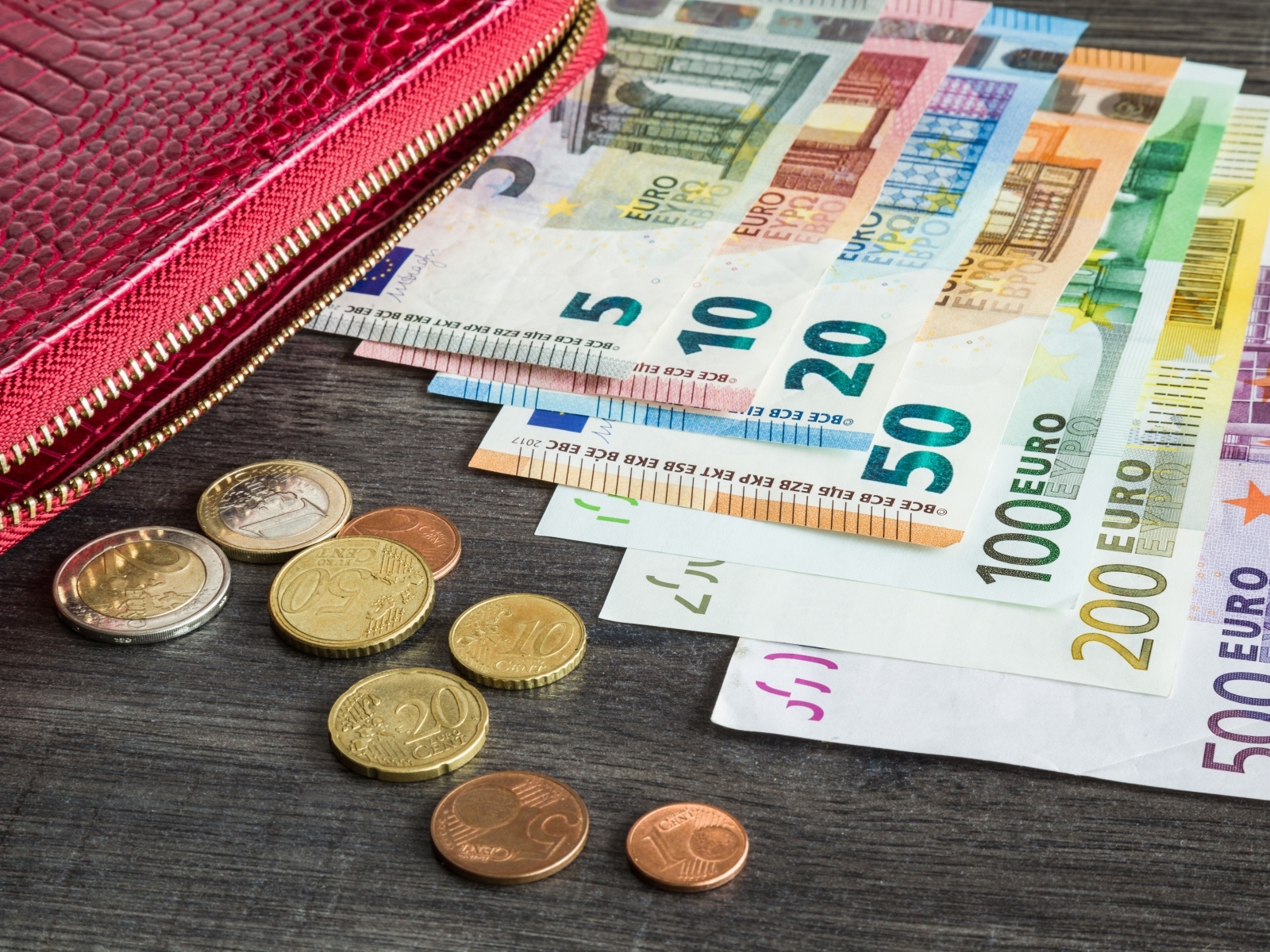 Купюры евро с монетами и кошельком на столе