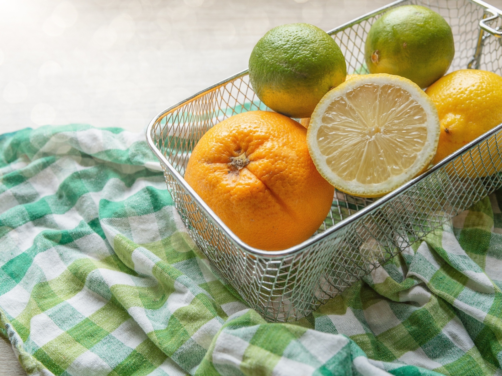 Цитрусовые фрукты в железной корзине на столе