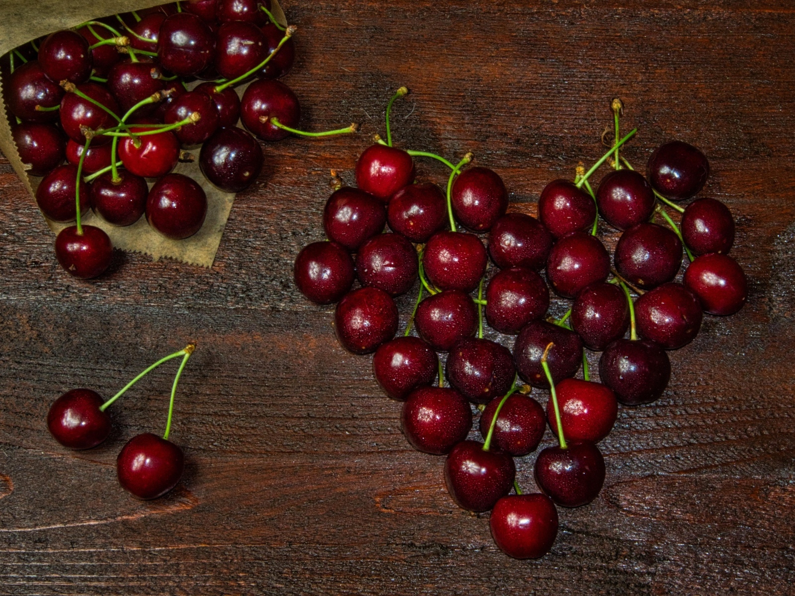 Сердце из спелых ягод черешни на деревянном столе