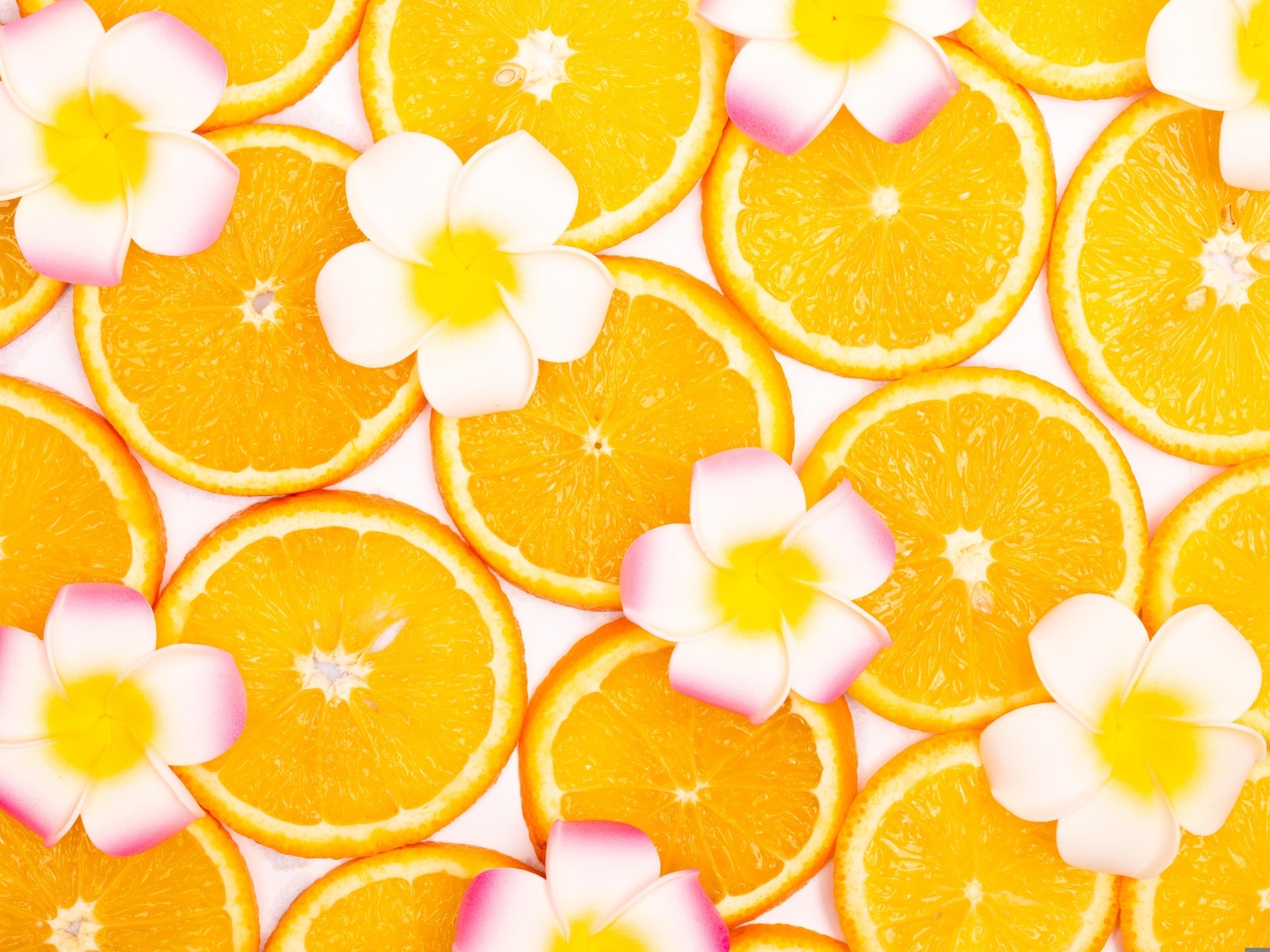 Нарезанный апельсин с цветами плюмерии для фона