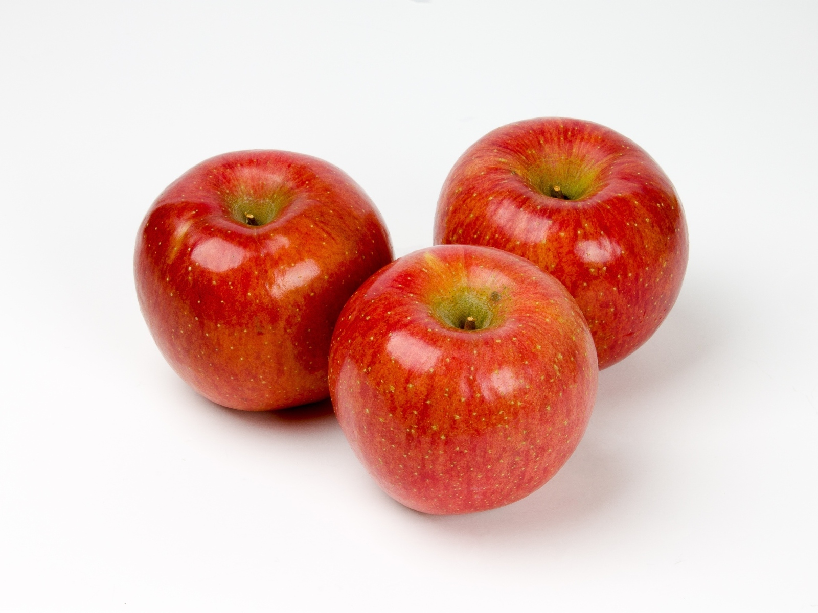 Три красных яблока на белом фоне