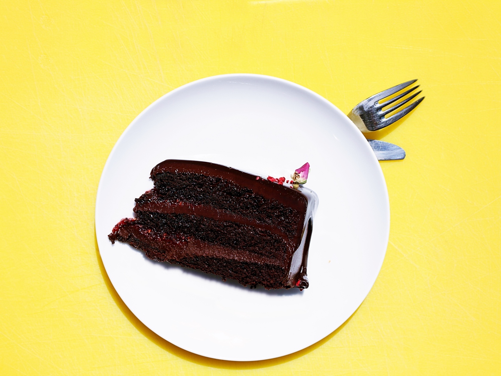 Кусок шоколадного торта на белой тарелке на желтом фоне