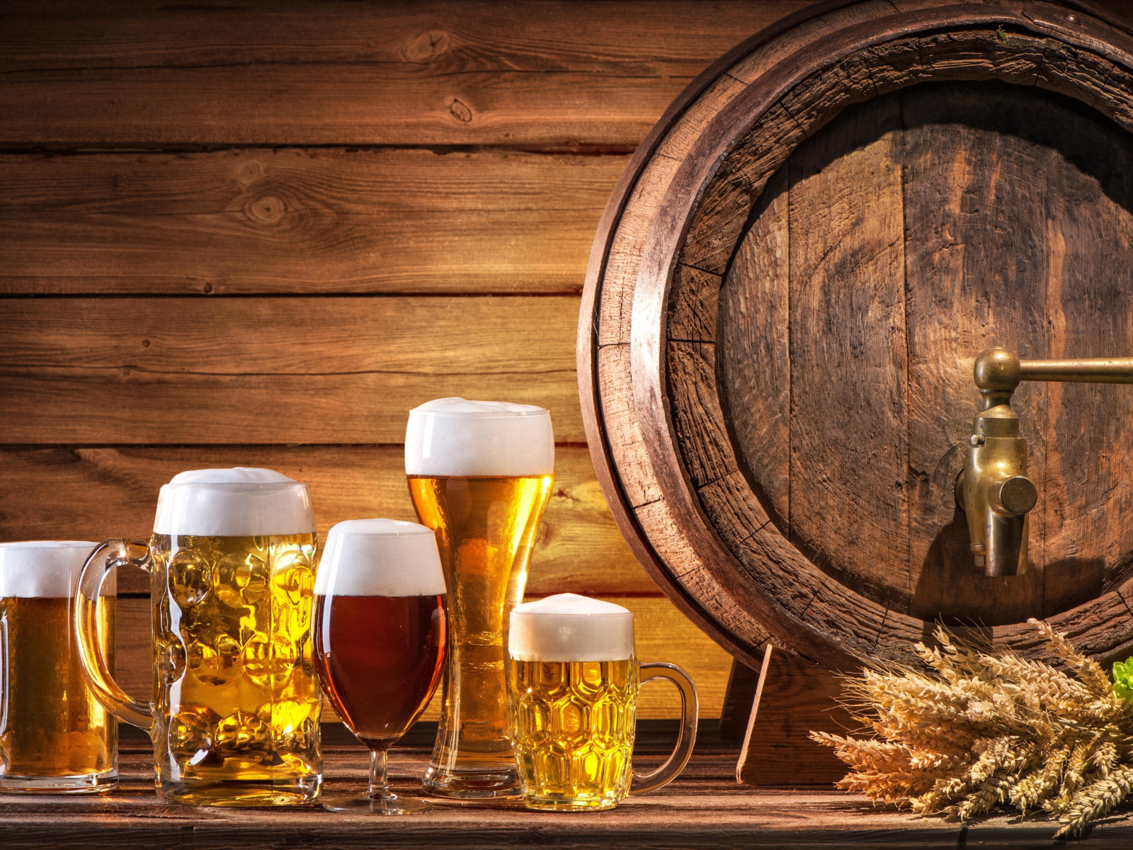 Бокалы с пивом на столе с бочкой 