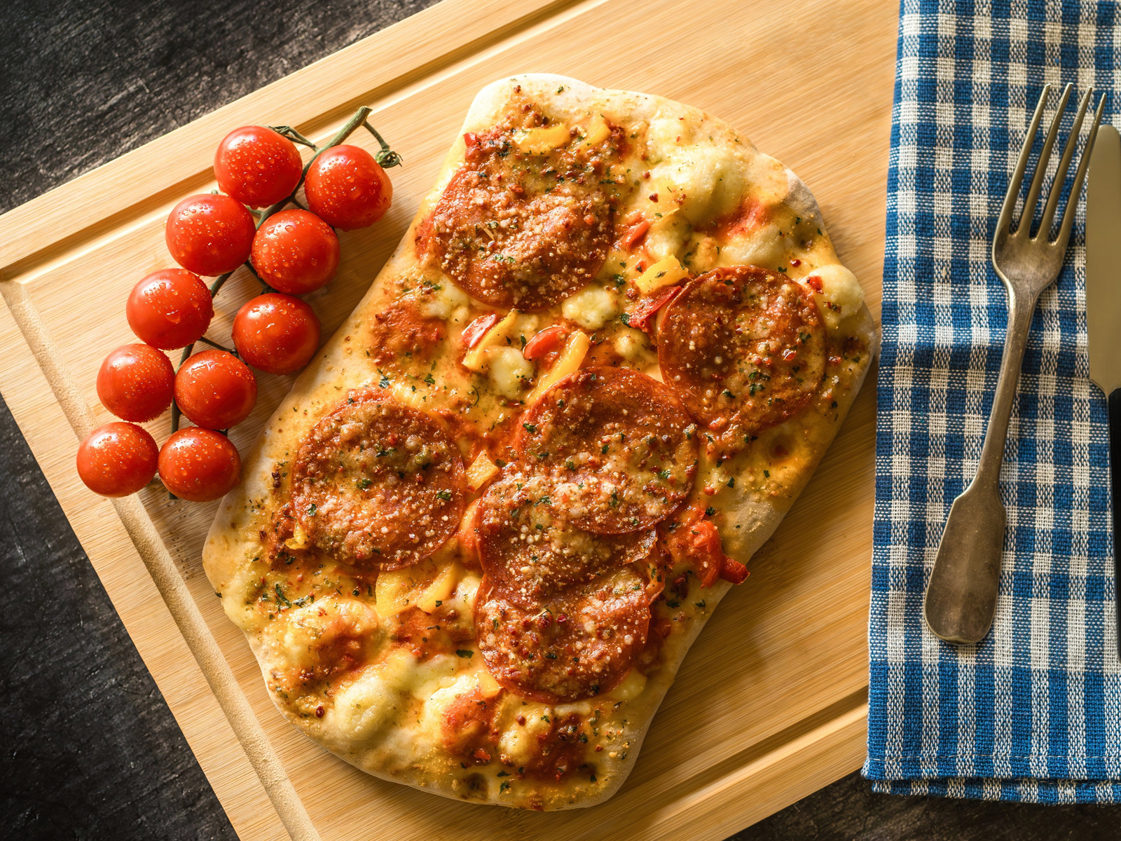 Пицца с колбасой и помидорами на доске