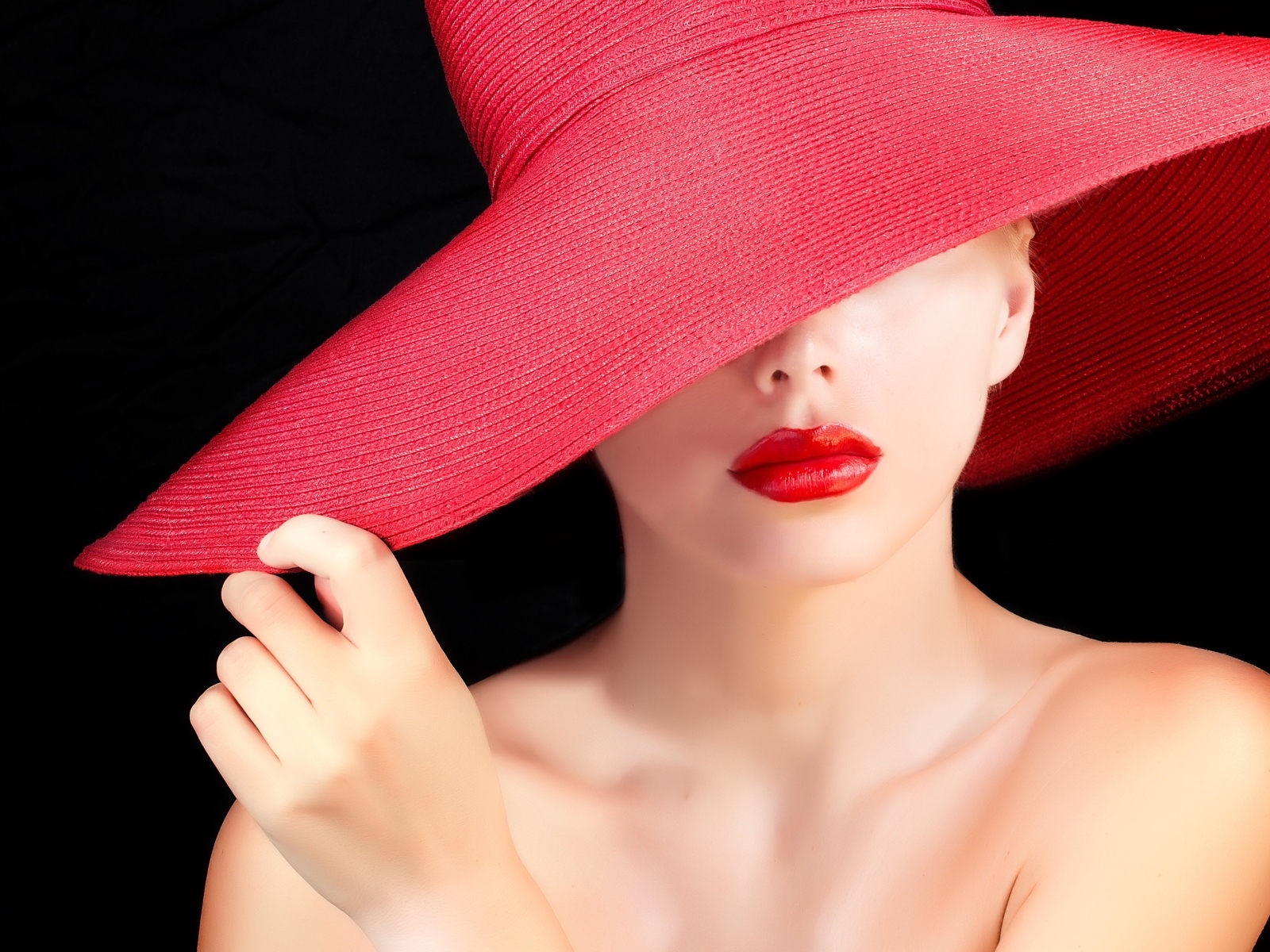 Девушка в большой красной шляпе на черном фоне