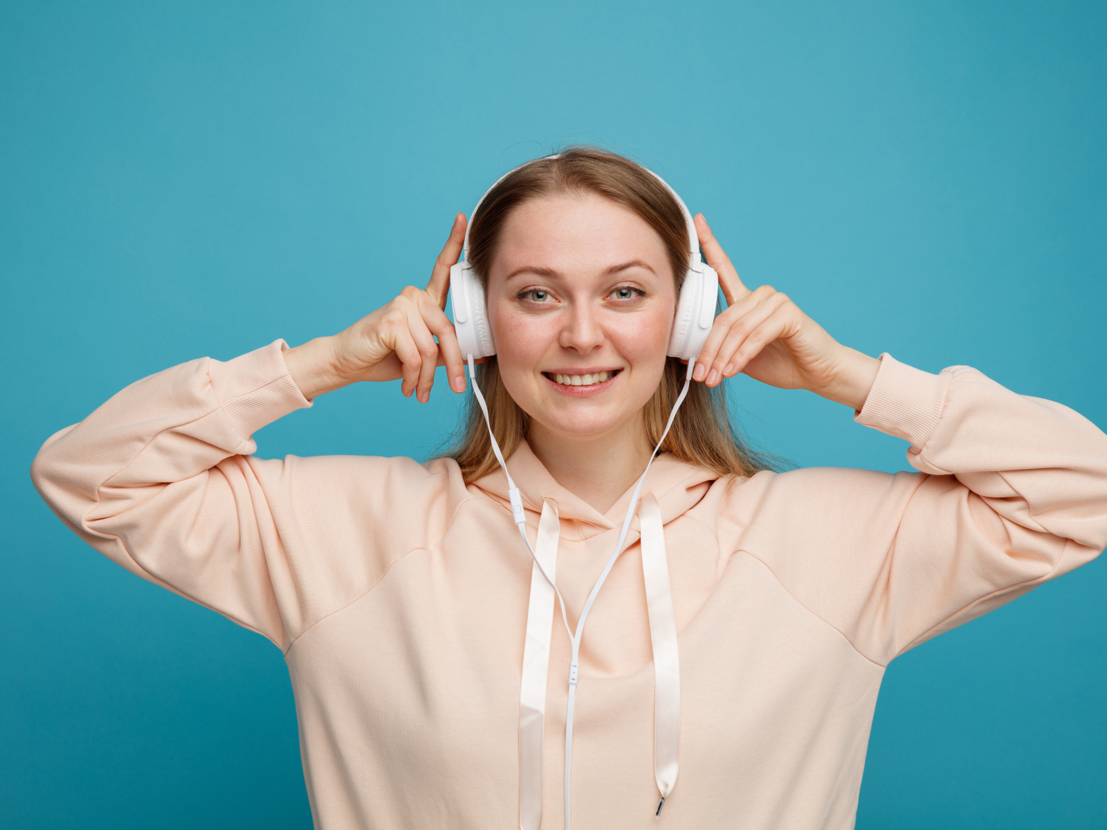 Улыбающаяся девушка в наушниках на голубом фоне