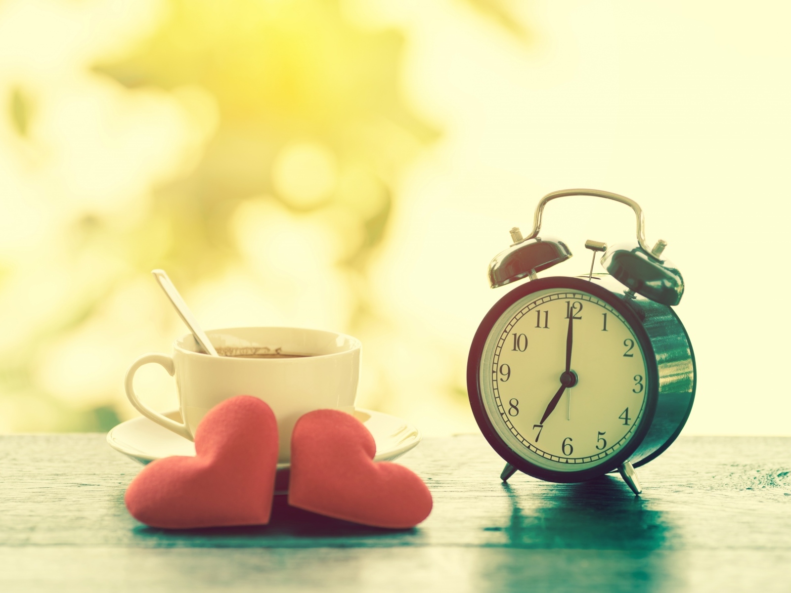 Будильник на столе с чашкой кофе и сердечками