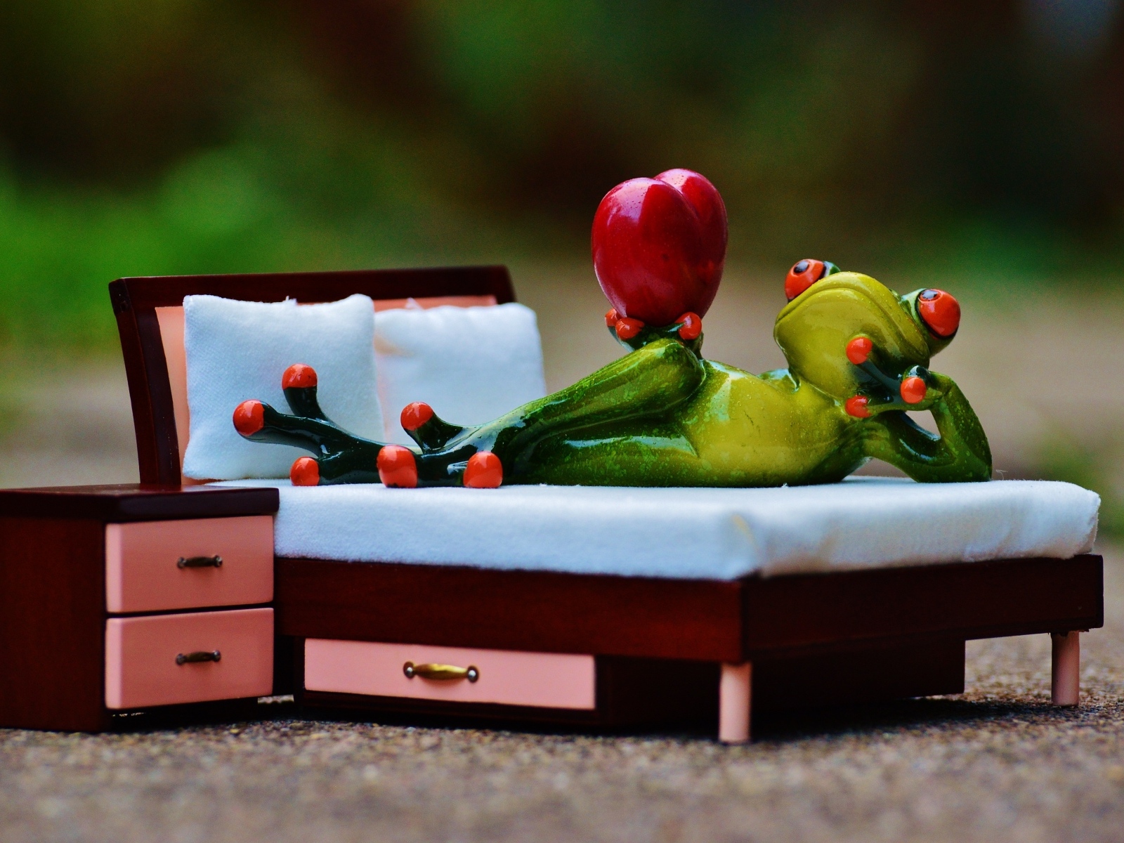 Фигурка зеленая лягушка с красным сердцем на кровати