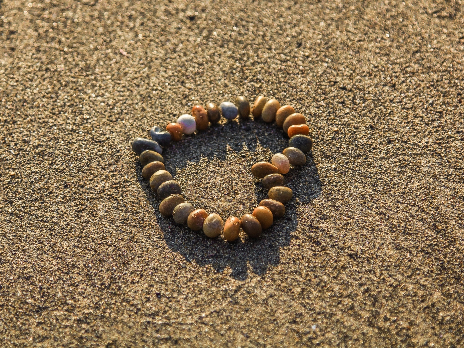 Сердце из камней на морском песке летом