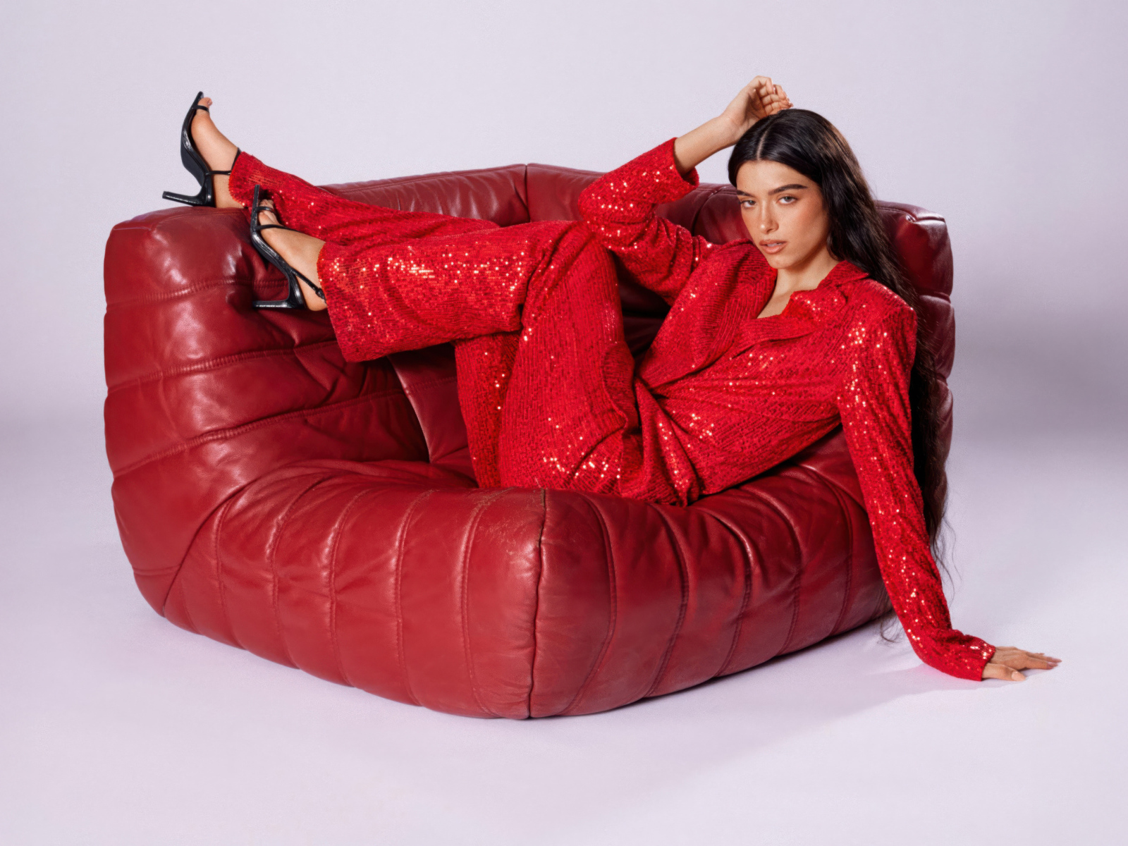 Певица Дикси Дамелио в красном костюме лежит в кресле