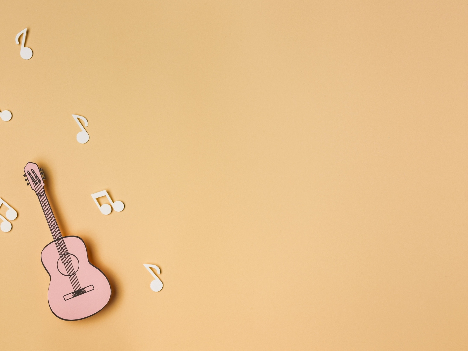 Маленькая гитара с нотами на бежевом фоне