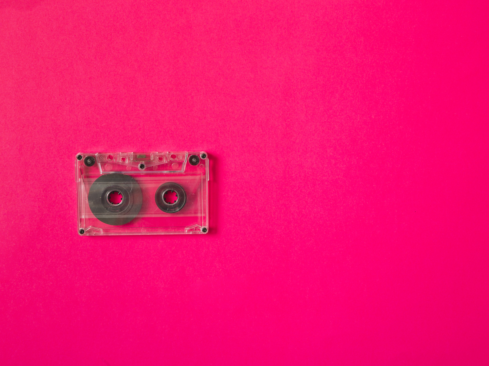 Маленькая магнитофонная кассета на розовом фоне