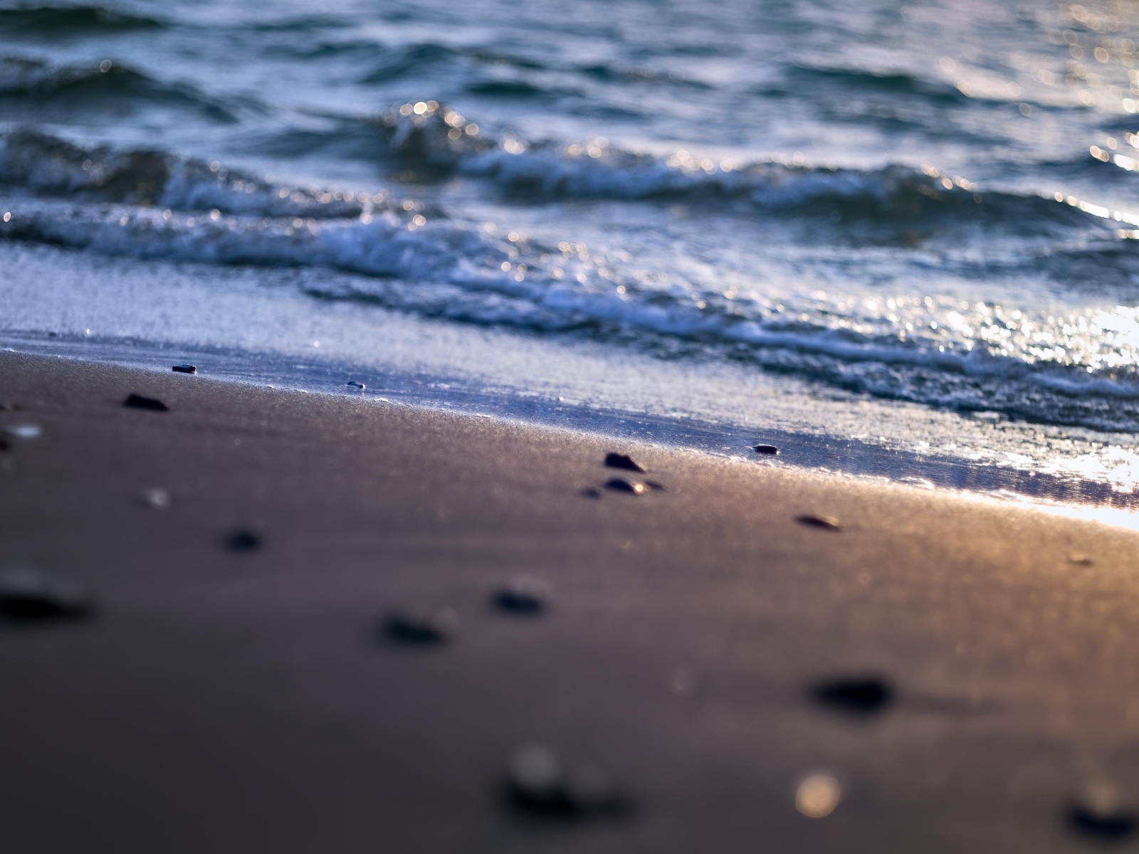 Мокрый морской песок омывает вода