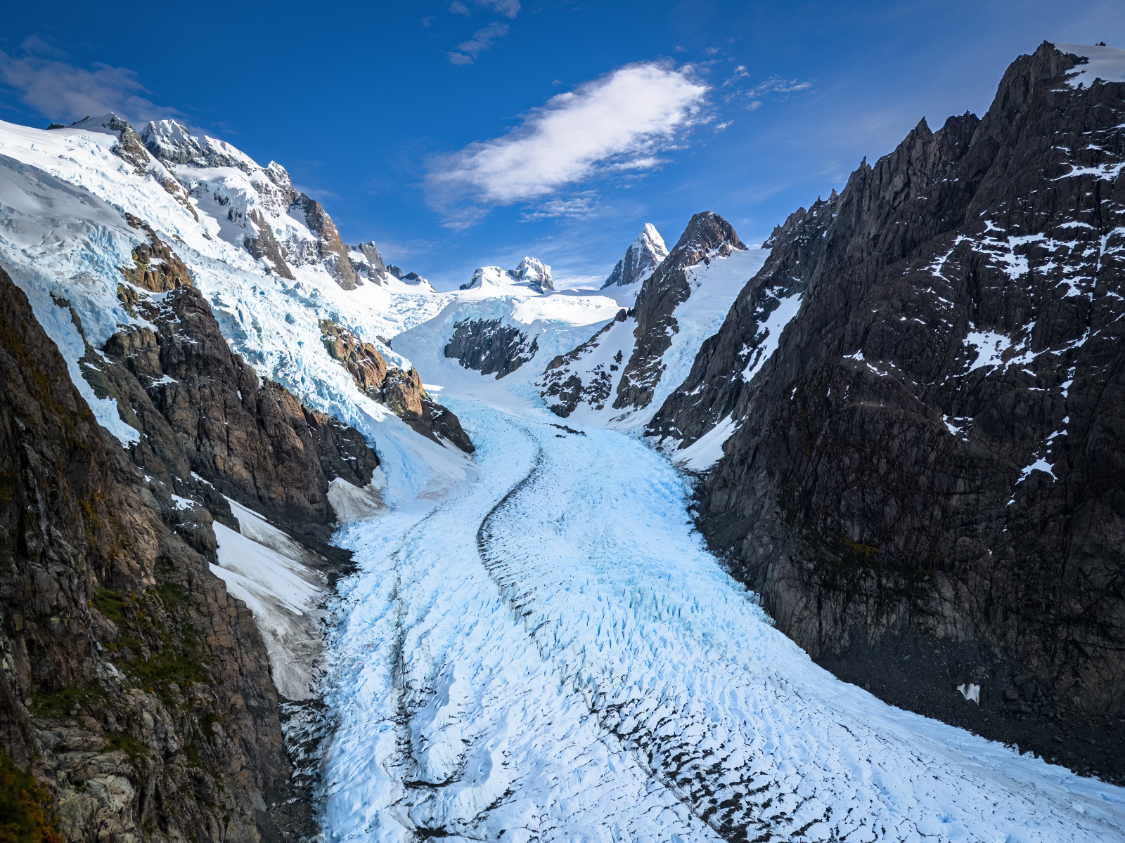 Заснеженная заледеневшая дорога между гор
