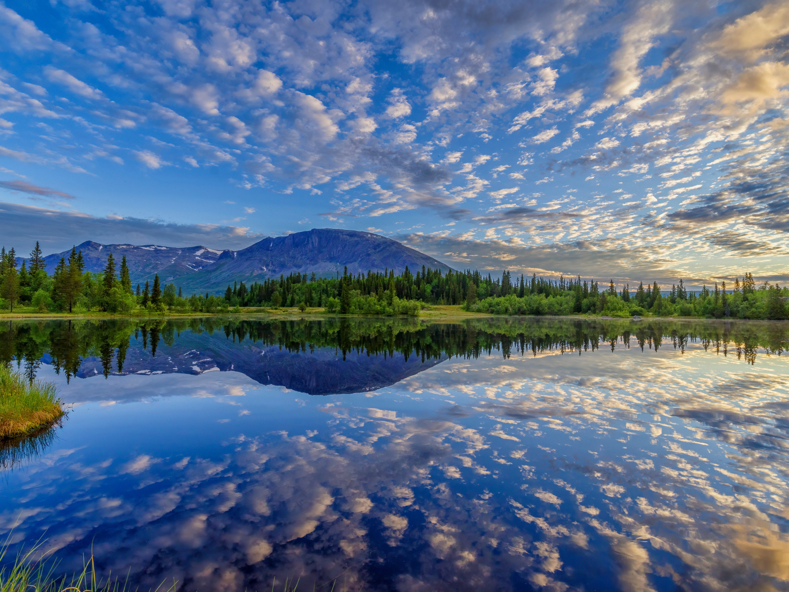 Красивое небо с облаками отражается в озере у гор