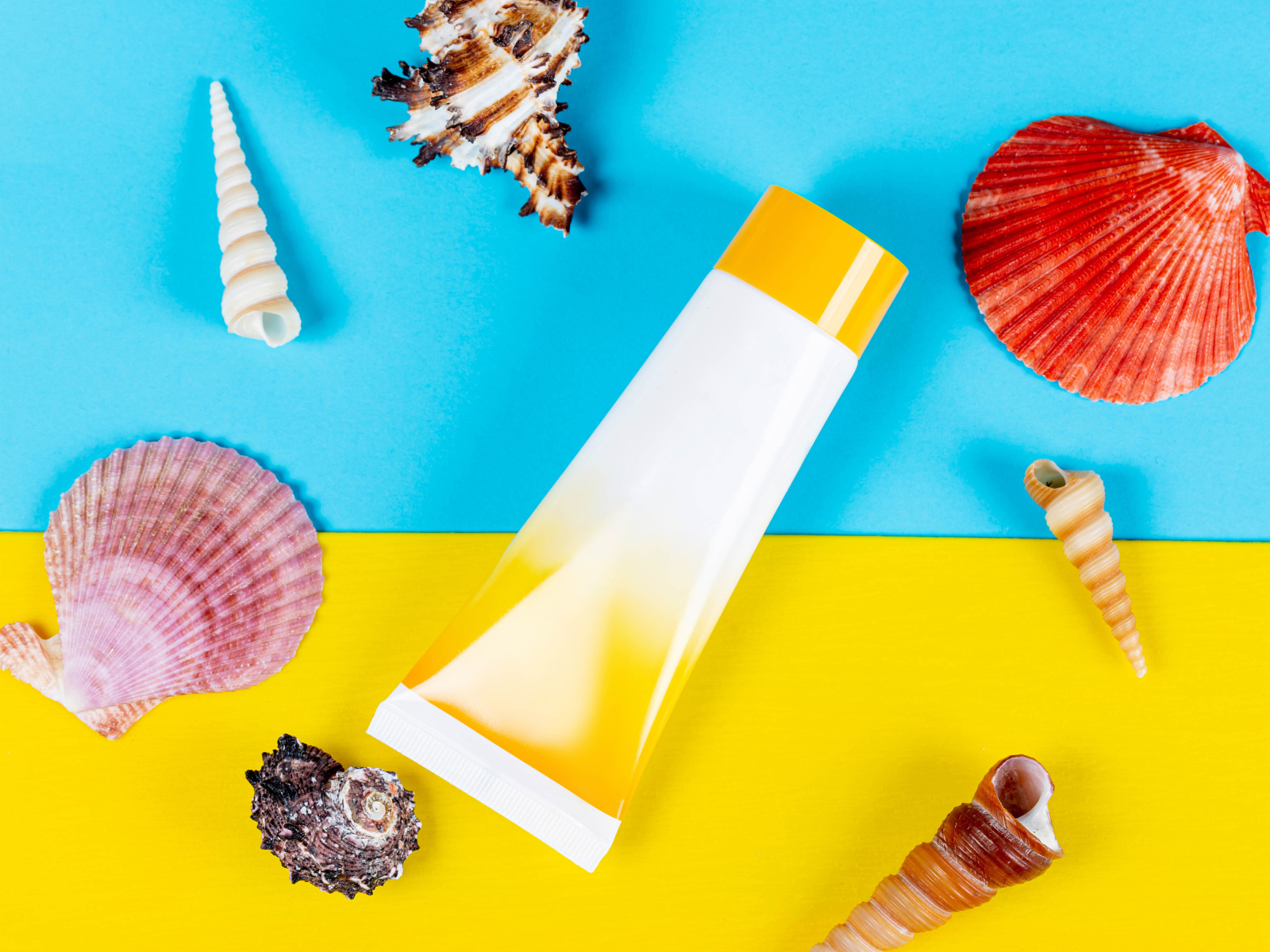 Крем от загара и ракушки на фоне