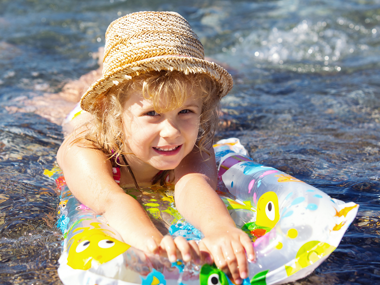 Девочка в шляпе плавает в воде