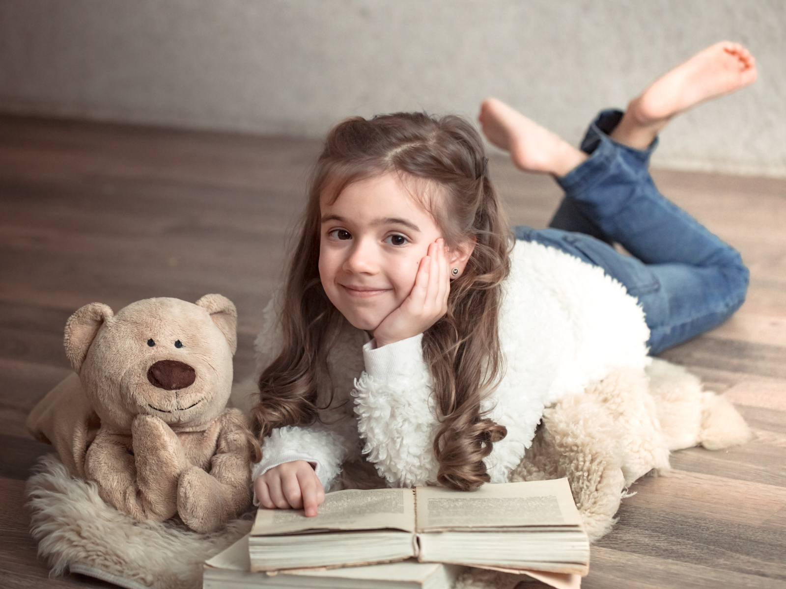 Девочка с медведем и книгой лежит на полу