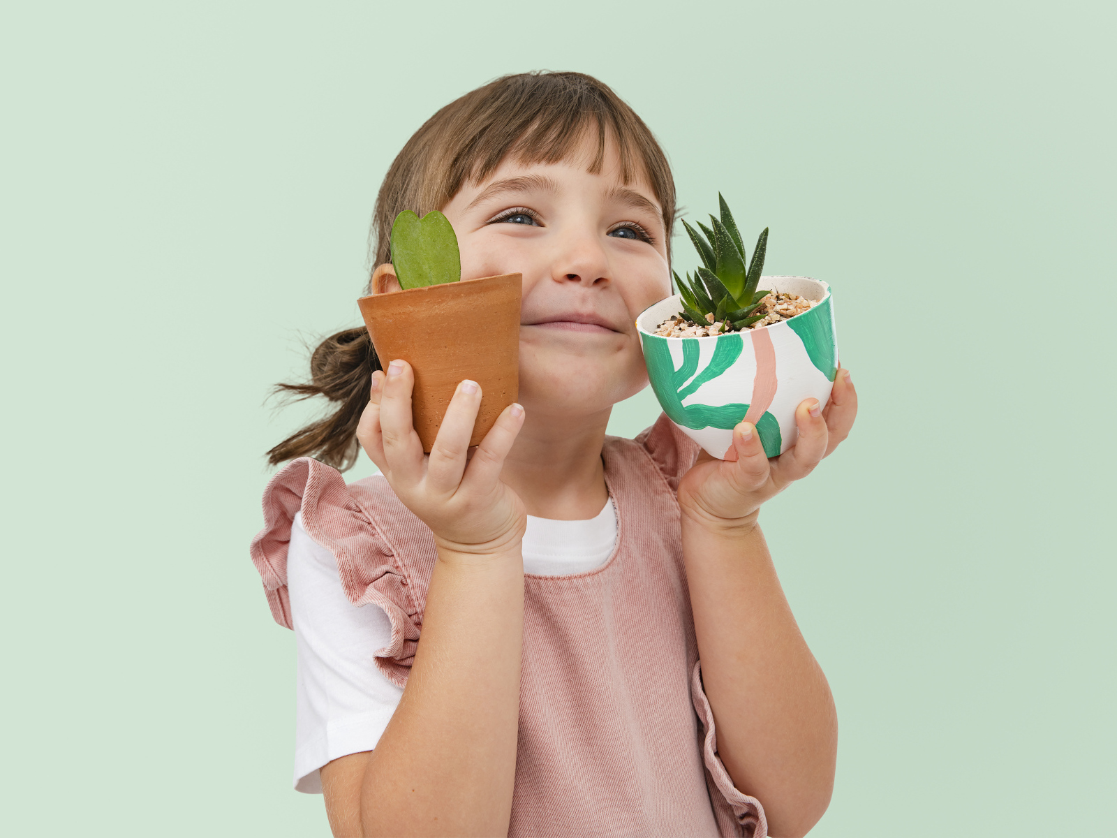 Маленькая девочка с комнатными цветами в руках