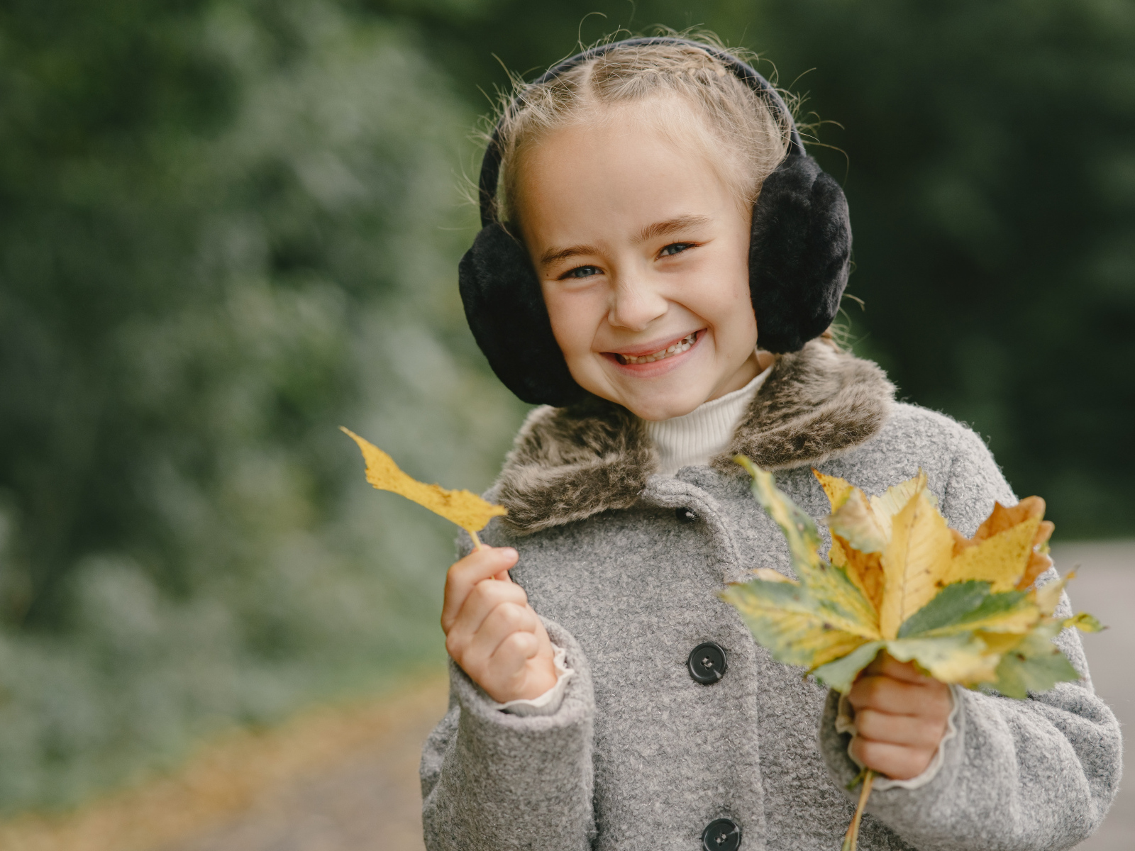 Улыбающаяся девочка с опавшими листьями в руках