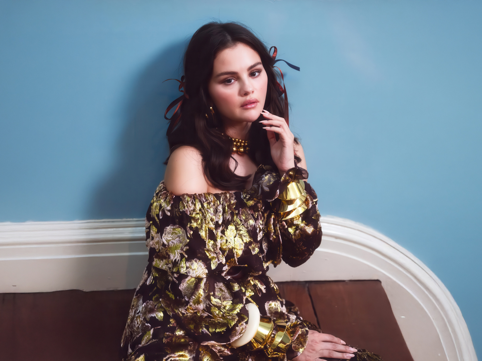 Актриса Селена Гомес на диване на фоне серой стены