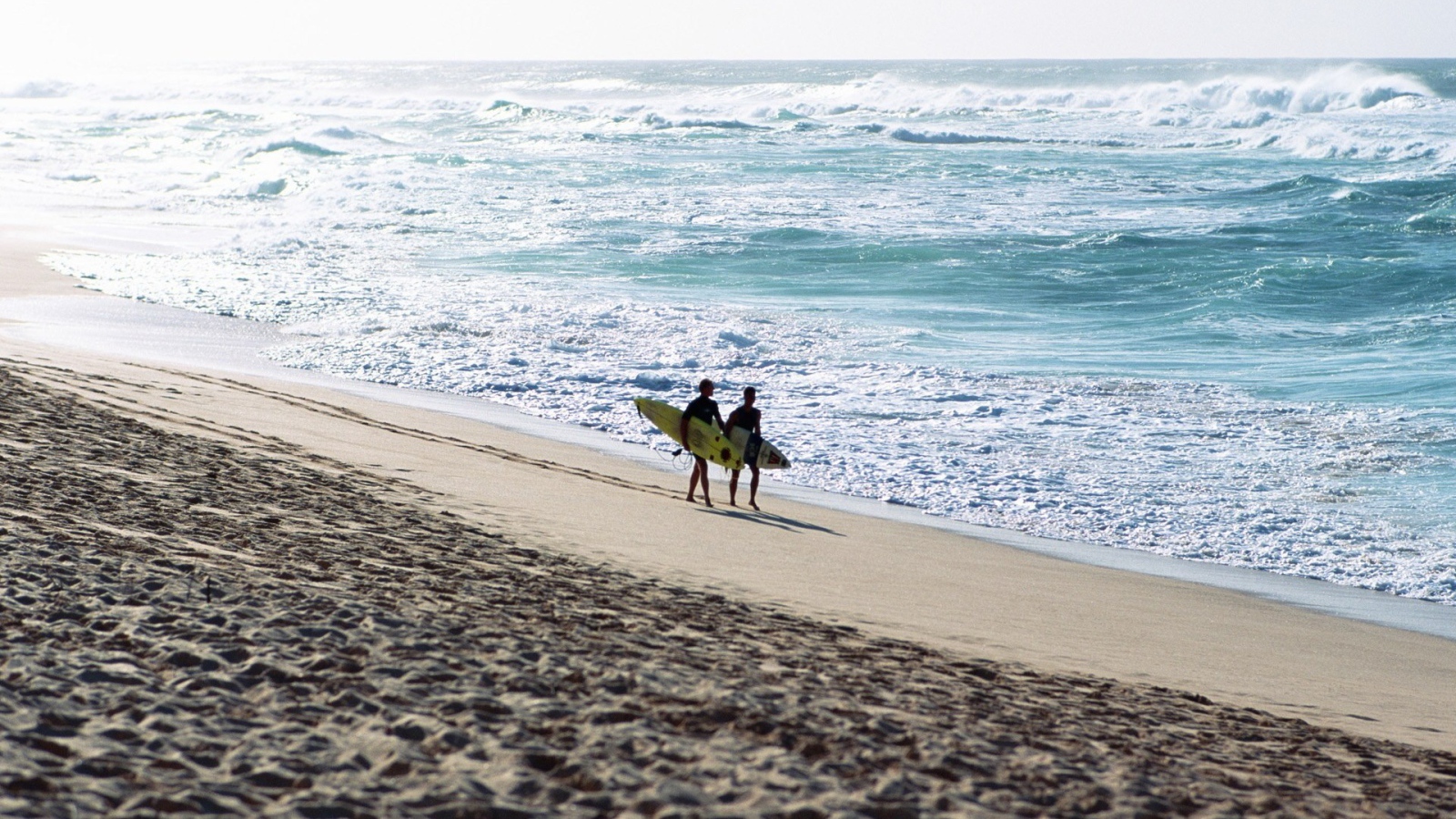 Два человека идут по пляжу